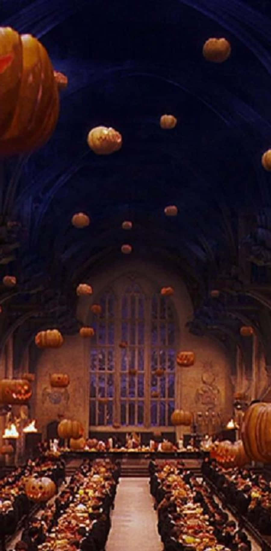 The Hogwarts Great Hall 桌布 壁紙 — 宏偉的哥德式大廳，充滿漂浮的南瓜和燭光餐桌，上方是拱形天花板。