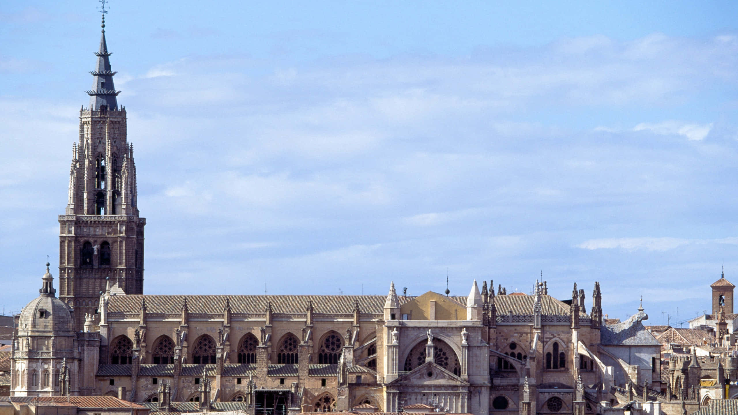 西班牙 桌布 壁紙 — 宏偉的哥德式大教堂，裝飾華麗的尖塔和拱形窗戶，聳立在部分多雲的藍天下。