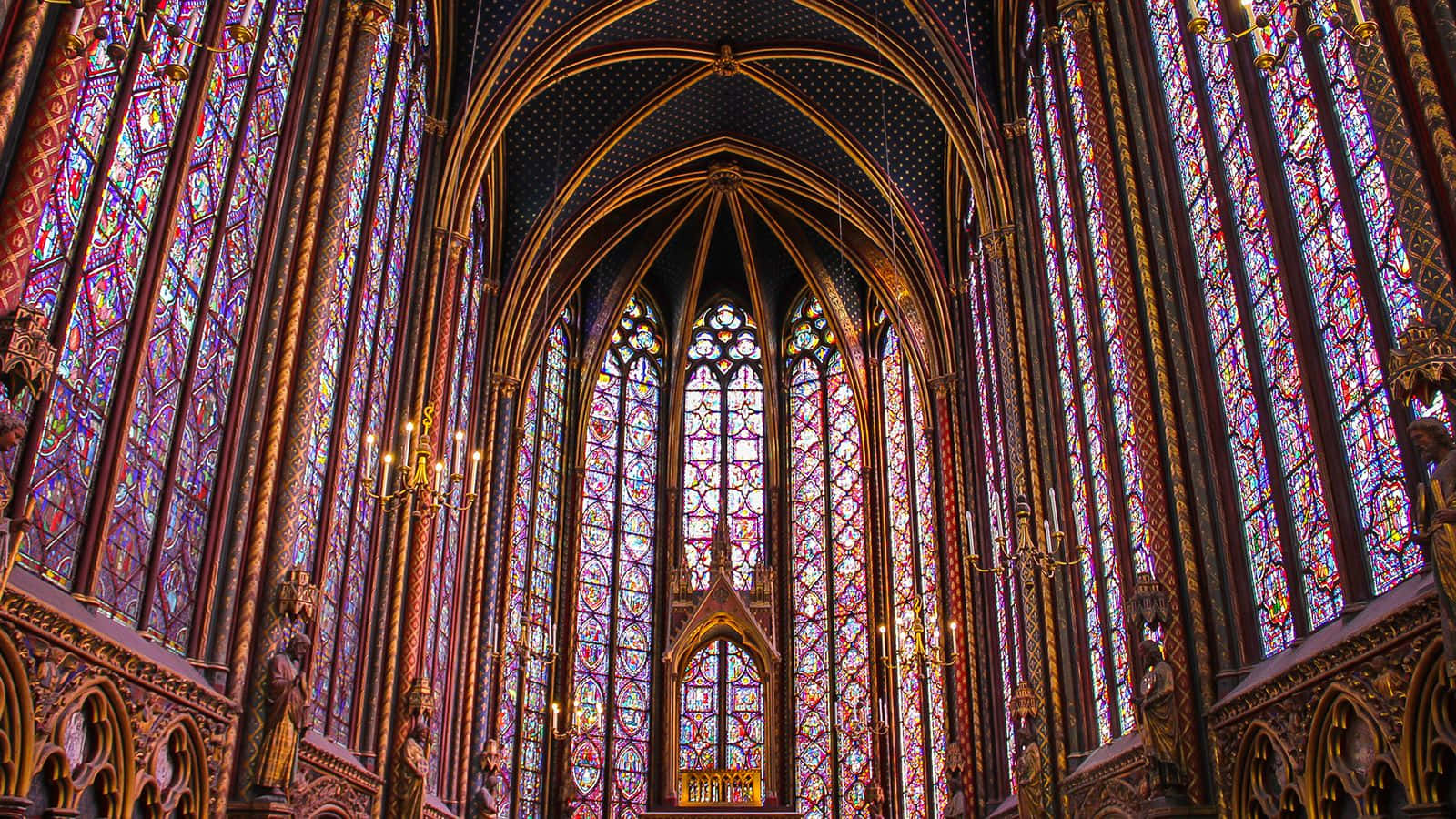 Gothic Architecture 桌布 壁紙 — 宏偉的哥德式大教堂內部，沐浴在高聳彩繪玻璃窗投射出的彩色光線中。