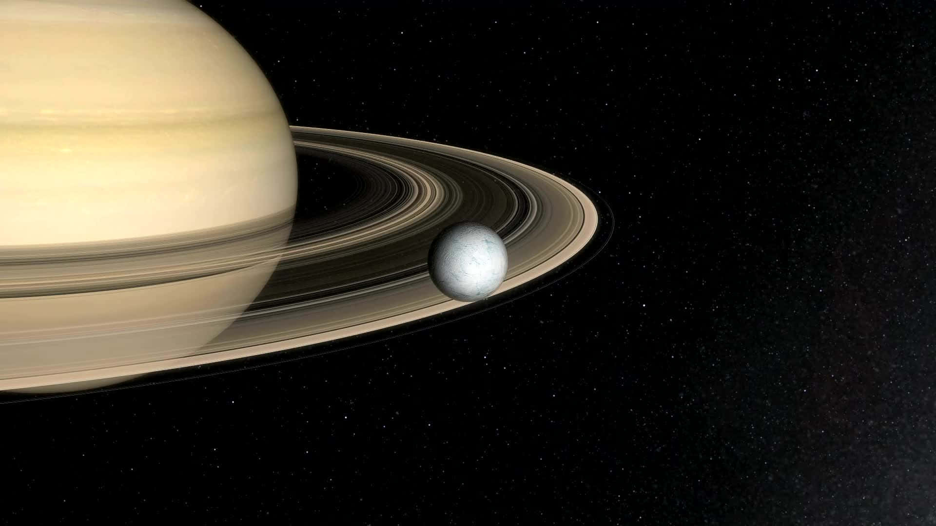 土星 桌布 壁紙 — 宏偉的土星以其標誌性的光環主宰著宇宙場景，一顆小衛星在附近繞行，背景是繁星點點的黑色虛空。