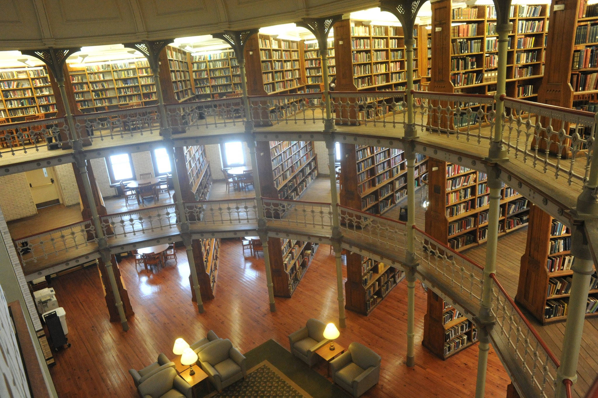 Library 桌布 壁紙 — 宏偉的多層圖書館，擁有高聳的木製書架、華麗的鐵欄杆和溫暖的燈光，營造出學術氛圍。