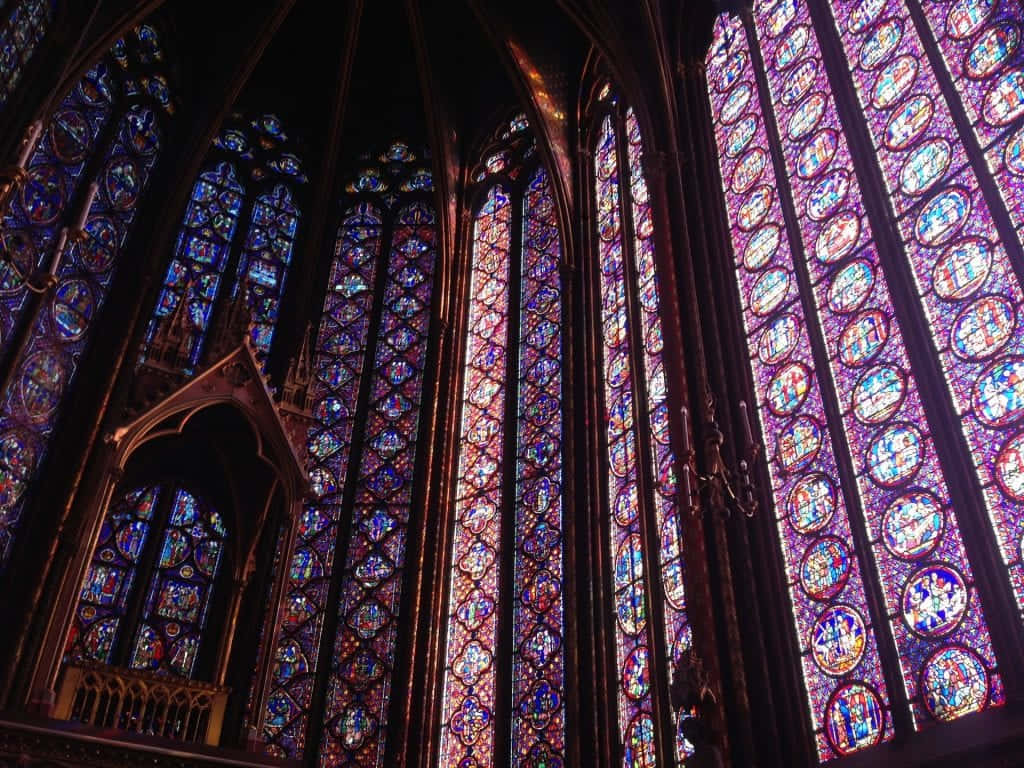 Gothic Architecture 桌布 壁紙 — 宏偉的大教堂內部，沐浴在透過高聳哥德式窗戶過濾的鮮豔彩繪玻璃光線中。
