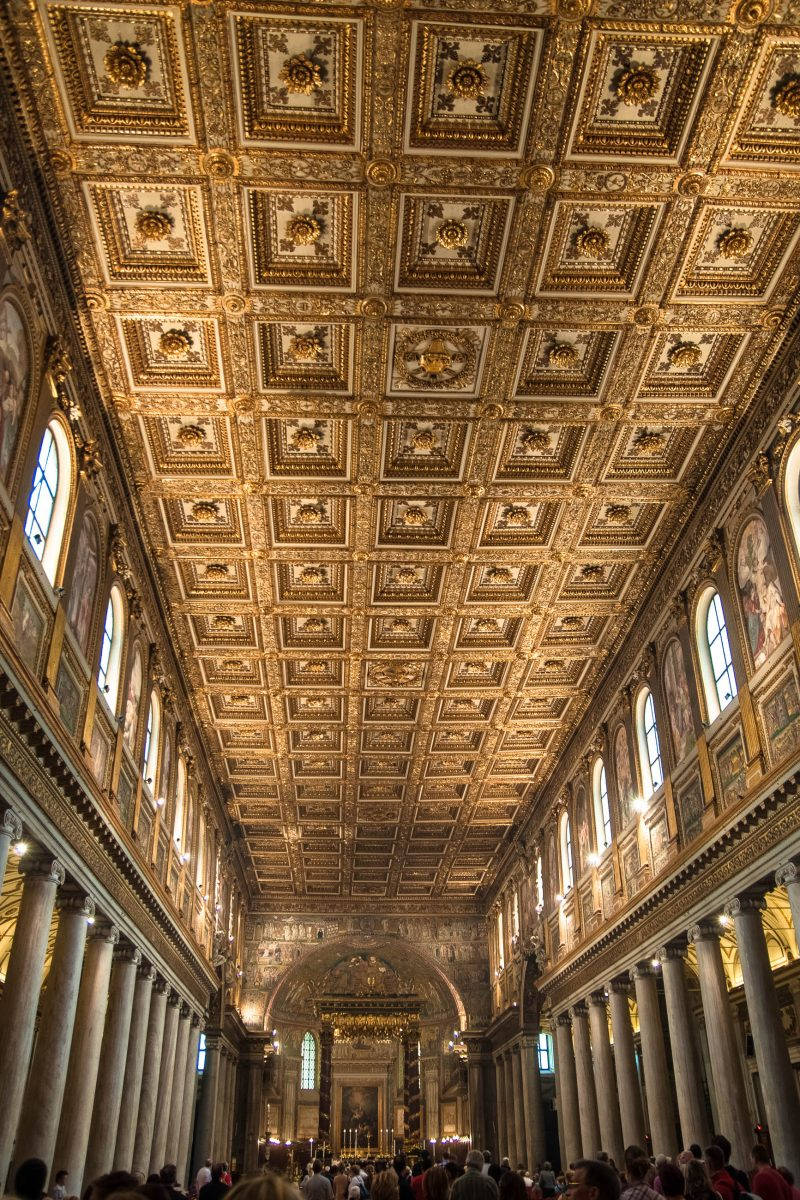 Rome 桌布 壁紙 — 宏偉的大教堂內部，金色方格天花板、大理石柱，下方信徒在溫暖光線中。
