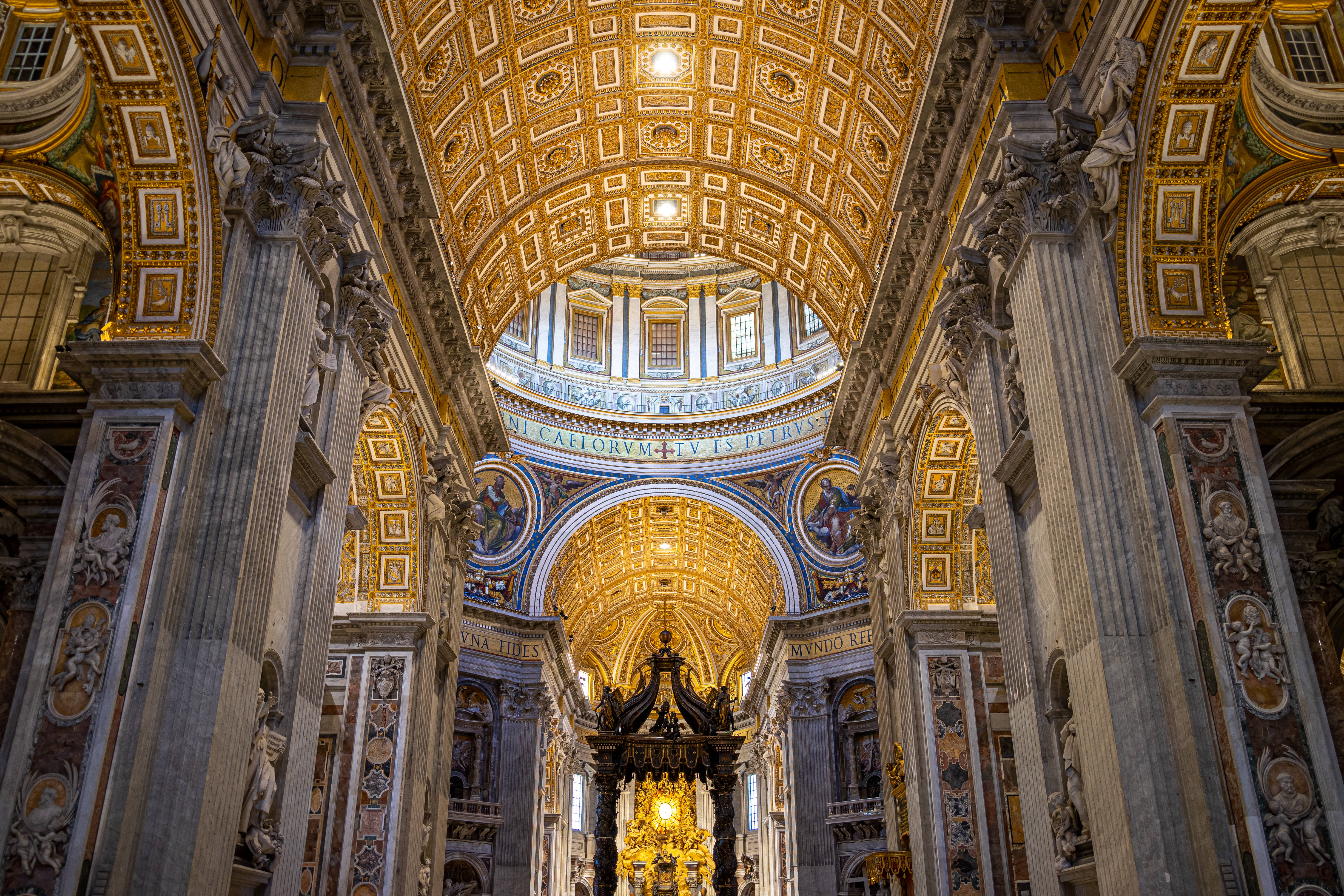 Vatican 桌布 壁紙 — 宏偉的大教堂內部，高聳的柱子、金色天花板和華麗的壁畫沐浴在溫暖的光線中。