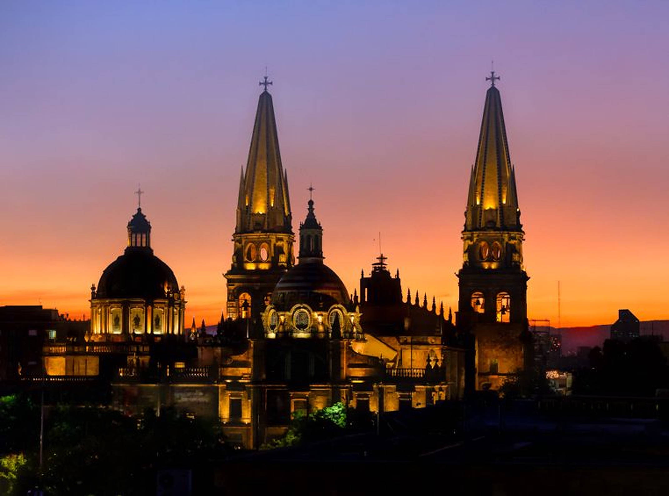 Guadalajara 桌布 壁紙 — 宏偉的大教堂塔樓和圓頂在橙紫色調的暮色天空中溫暖地發光。
