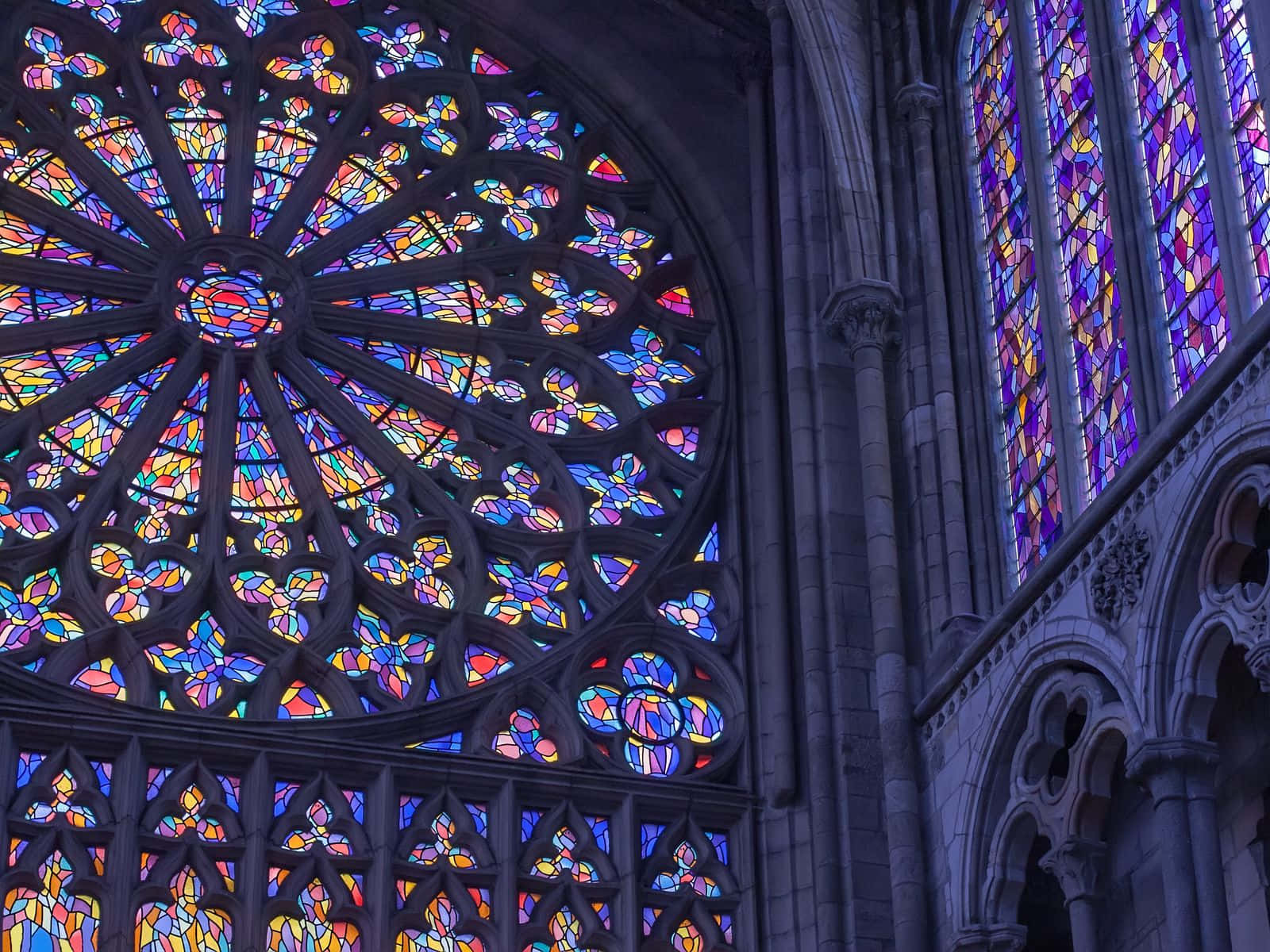 Stained Glass 桌布 壁紙 — 宏偉的大教堂玫瑰窗在石拱門和柱子間散發出鮮豔的彩繪玻璃色彩。