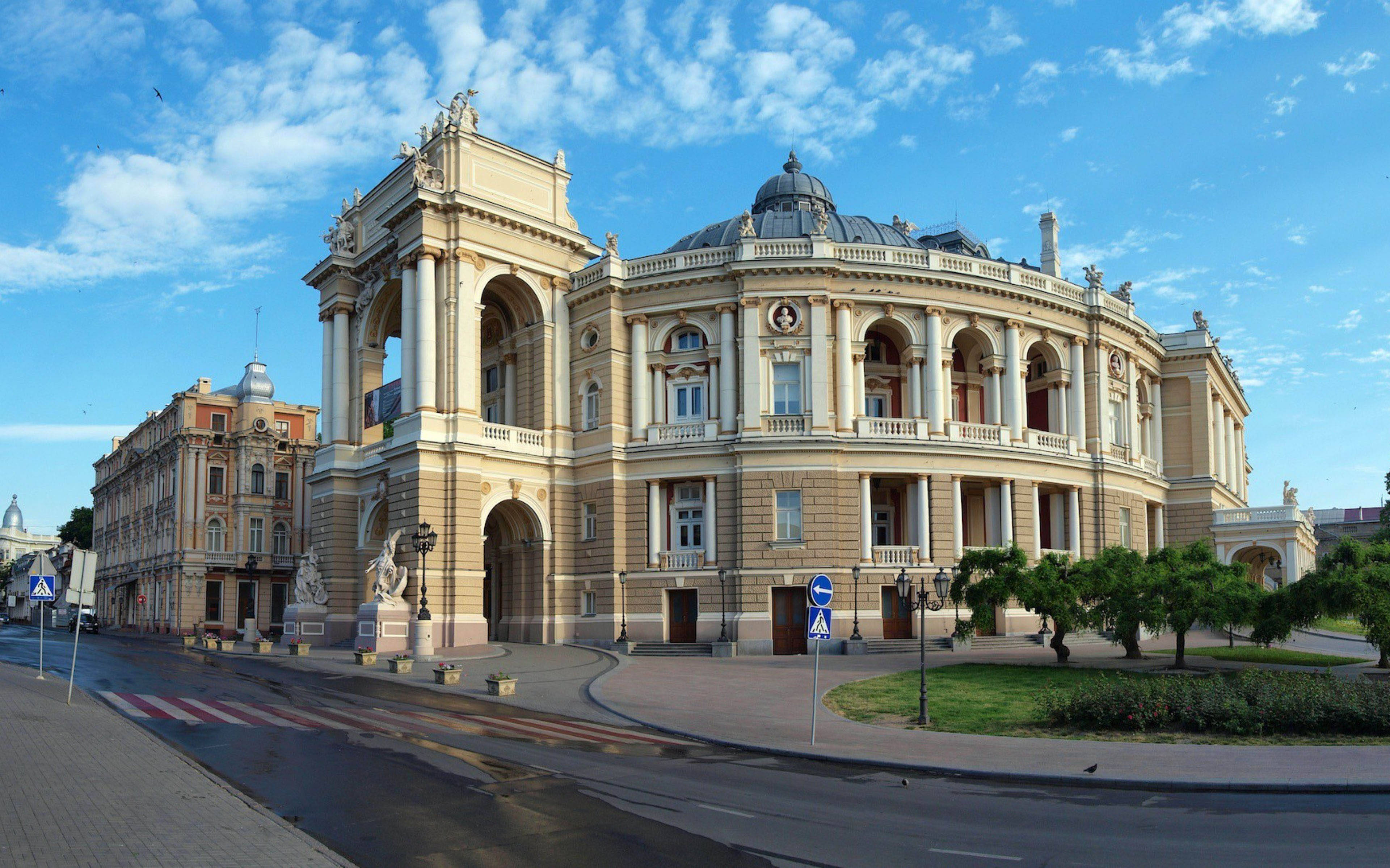 Ukraine 桌布 壁紙 — 宏偉的新古典主義劇院，擁有華麗的柱子和圓頂屋頂，矗立在晴朗藍天和零星白雲下。
