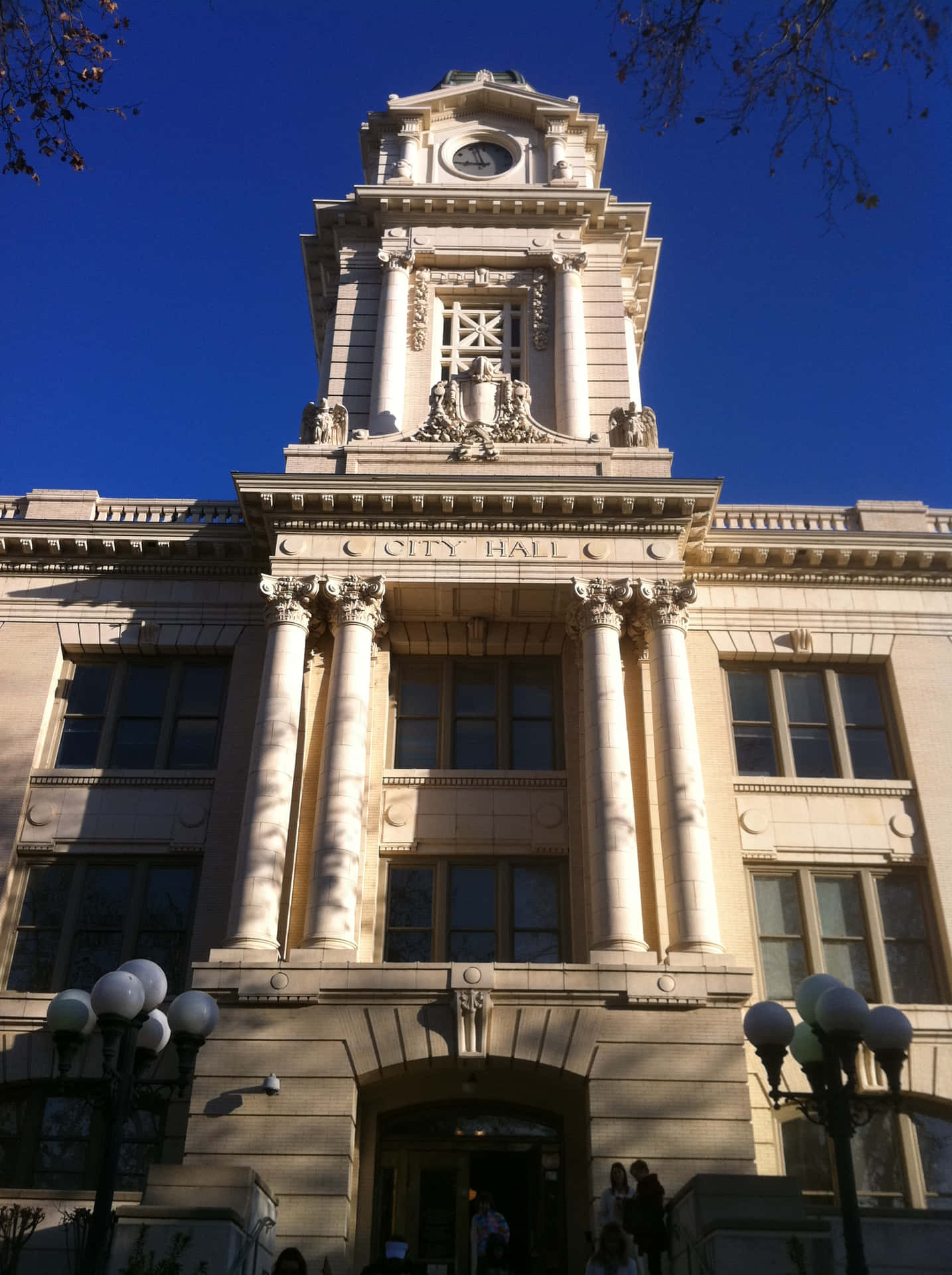 城市 桌布 壁紙 — 宏偉的新古典主義市政廳，擁有華麗的柱子和鐘樓，在晴朗的藍天下沐浴在明亮的陽光中。