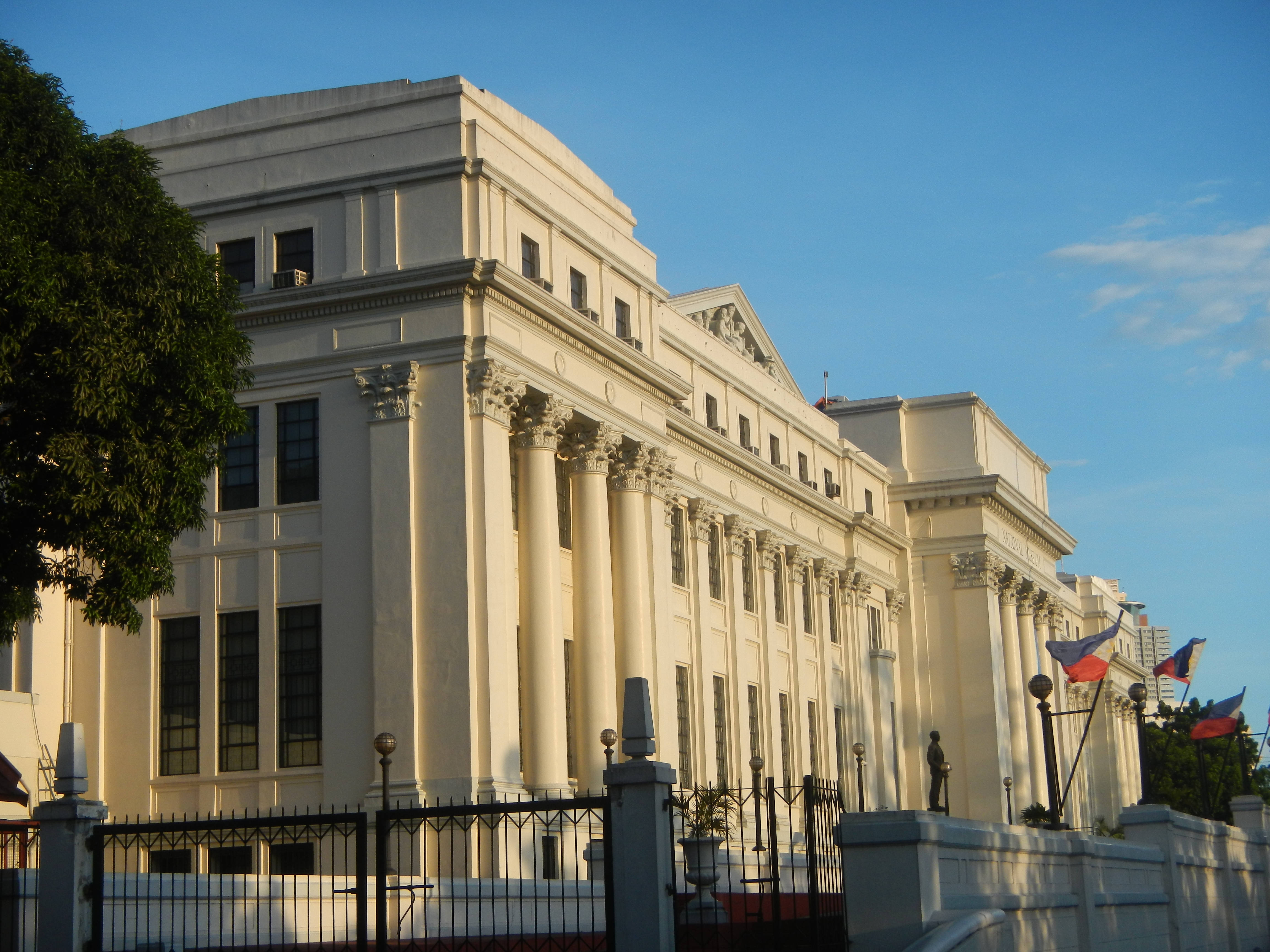 Manila 桌布 壁紙 — 宏偉的新古典主義政府建築，高聳的柱子沐浴在金色晨光下，天空湛藍清澈。
