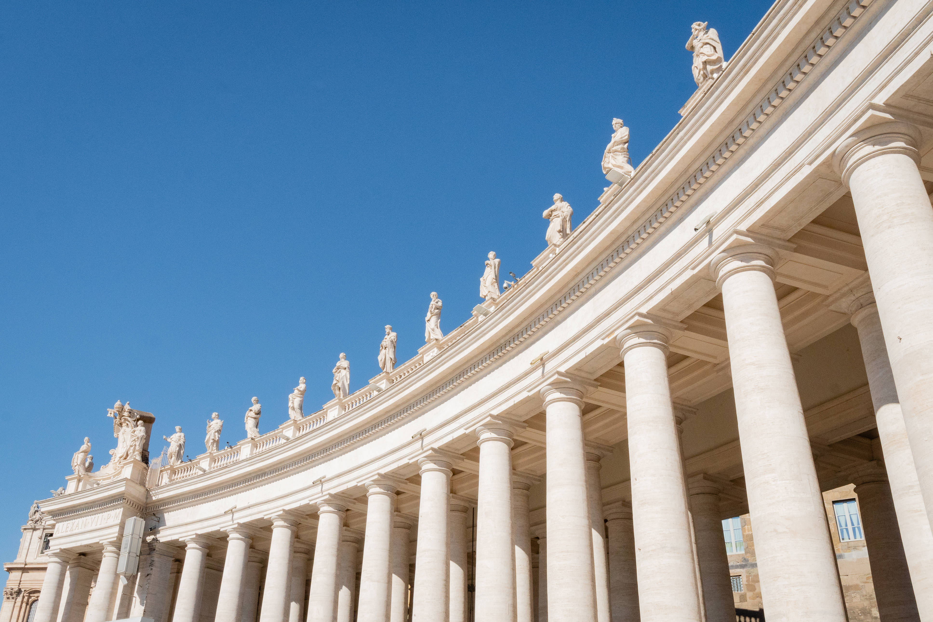 Vatican 桌布 壁紙 — 宏偉的柱廊，白色大理石柱和雕像，在清澈的藍天下。