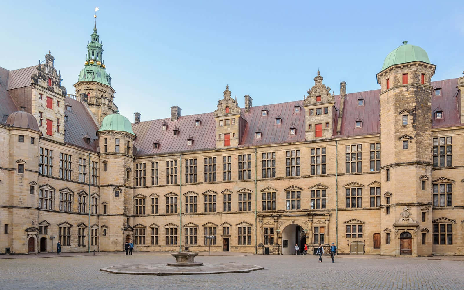 Denmark 桌布 壁紙 — 宏偉的歷史城堡庭院，擁有石頭建築、銅屋頂和綠色圓頂，在晴朗的藍天下。