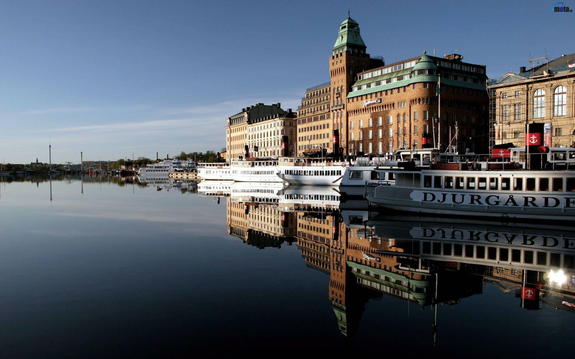 Sweden 桌布 壁紙 — 宏偉的歷史建築和白色渡輪在晴朗的藍天下完美地倒映在平靜的水面上。