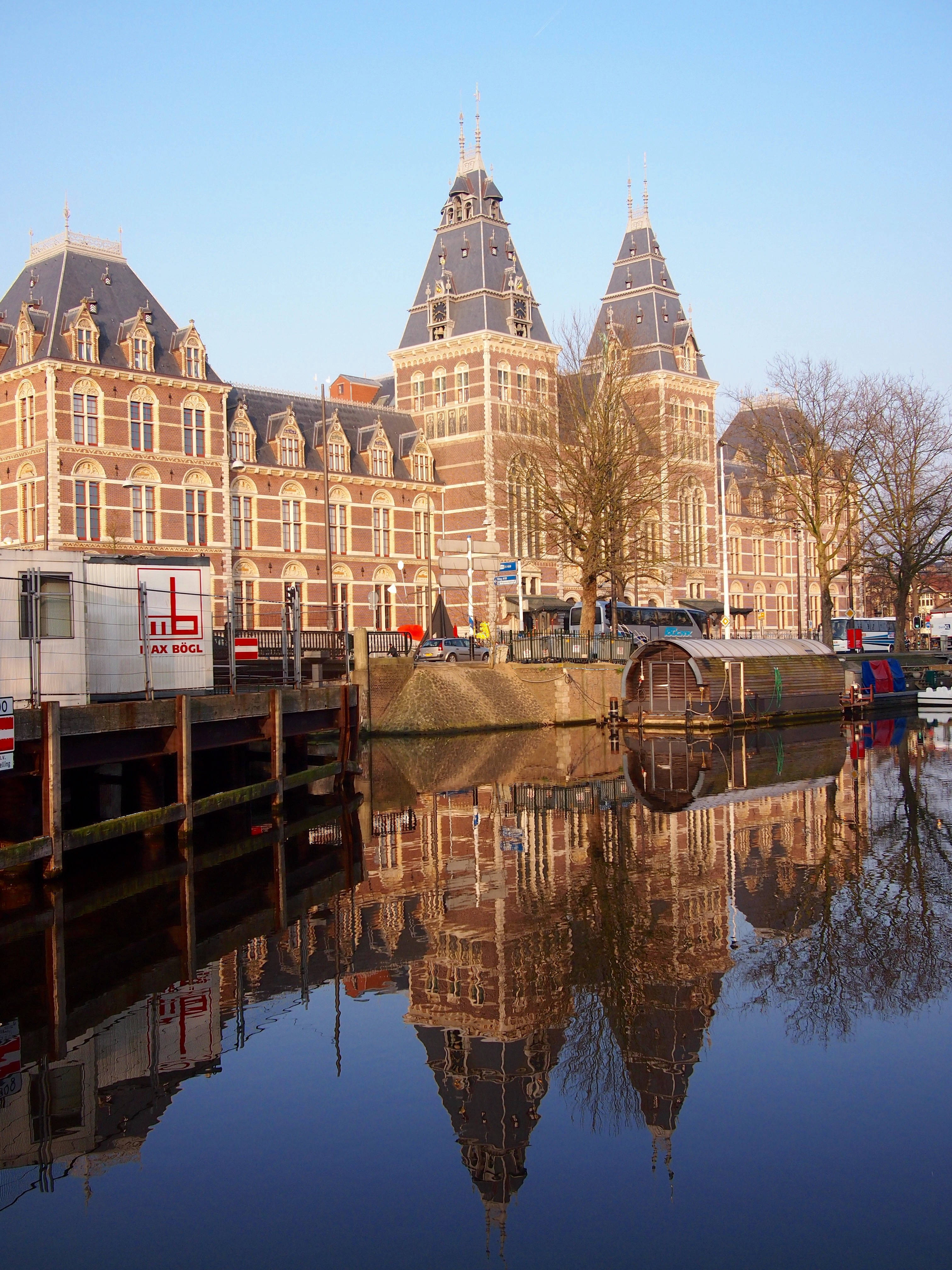 Netherlands 桌布 壁紙 — 宏偉的歷史建築物，帶有華麗的塔樓，在晴朗的藍天下完美地倒映在平靜的運河水中。
