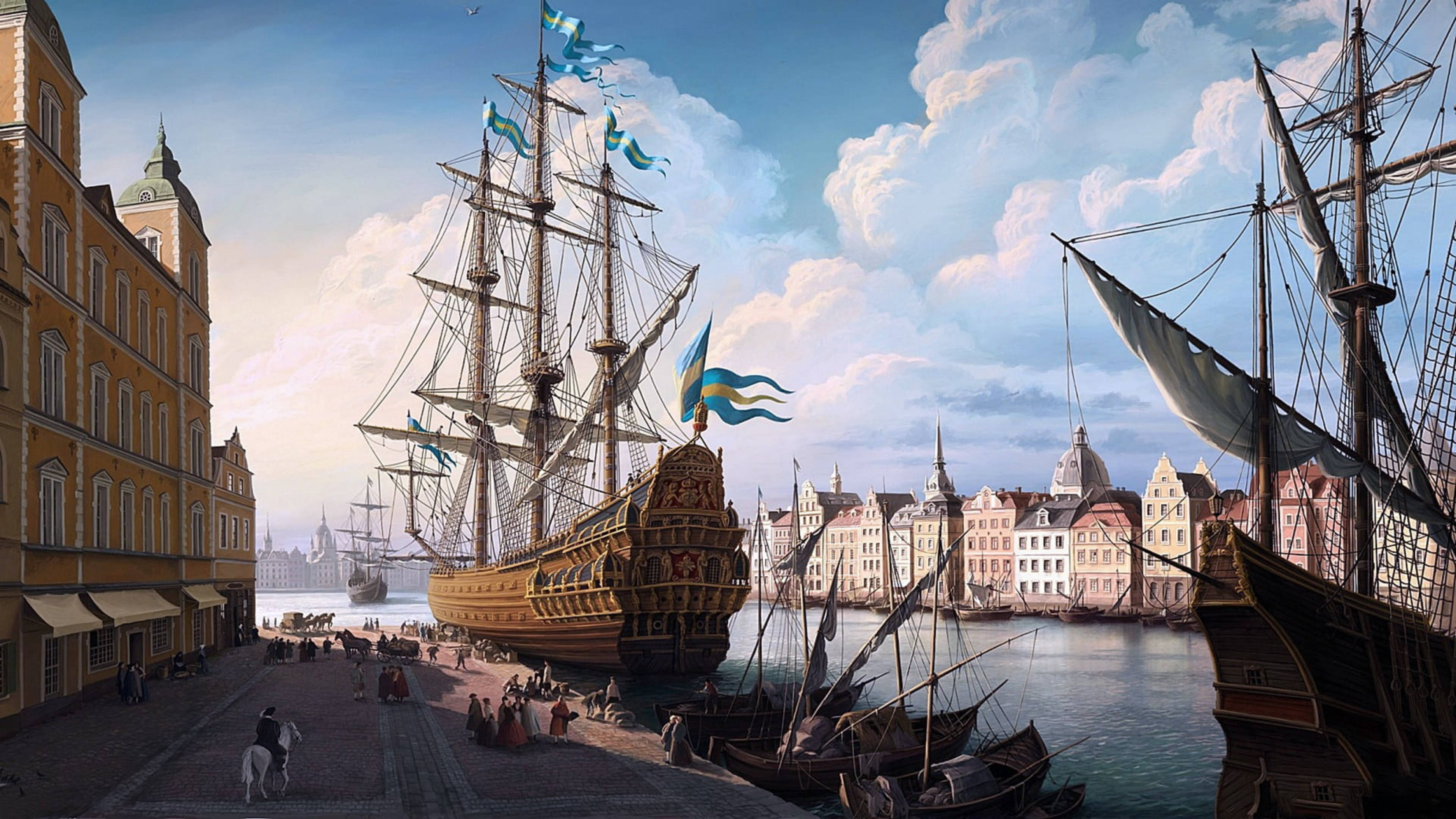 Sailing Ship 桌布 壁紙 — 宏偉的歷史港口場景，裝飾華麗的加利恩帆船懸掛著藍黃旗幟，停泊在色彩繽紛的歐洲建築旁，天空明亮多雲。