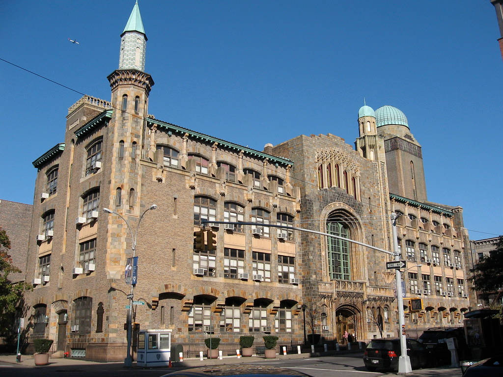 建築 桌布 壁紙 — 宏偉的歷史石建築，擁有華麗的塔樓和拱形窗戶，在清澈的藍天下。
