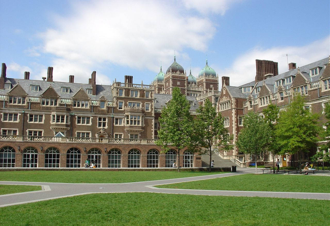 Building 桌布 壁紙 — 宏偉的歷史磚砌大學建築，帶有綠色圓頂，在部分多雲的藍天下，從修剪整齊的草坪後方升起。