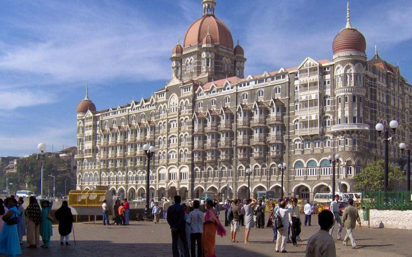 Mumbai 桌布 壁紙 — 宏偉的殖民風格泰姬瑪哈皇宮酒店，擁有圓頂和陽台，在明亮的藍天下，前景有遊客聚集。