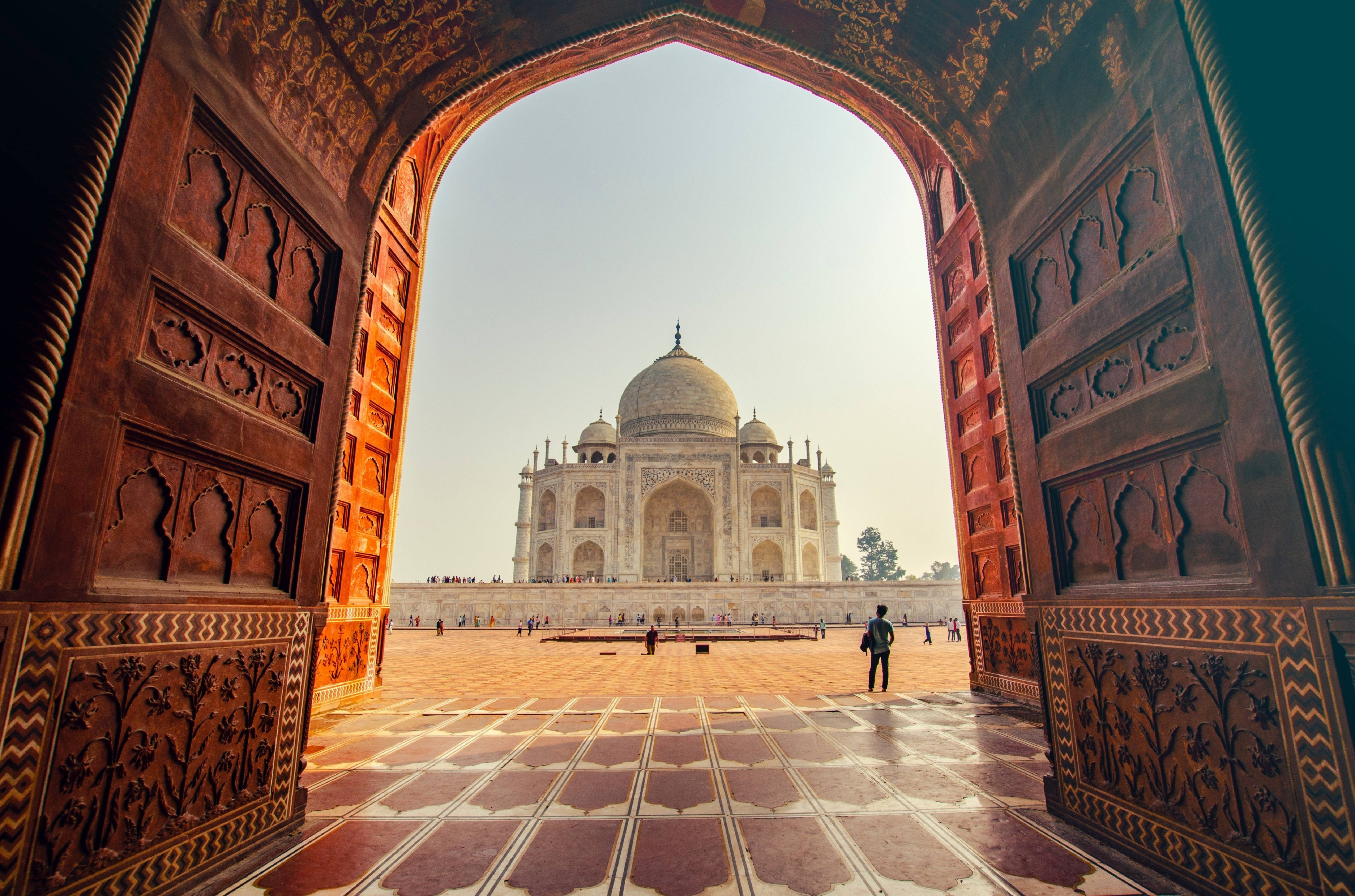 Delhi 桌布 壁紙 — 宏偉的泰姬陵景觀，由一個裝飾華麗的拱門框住，拱門上有精緻的雕刻和瓷磚庭院。