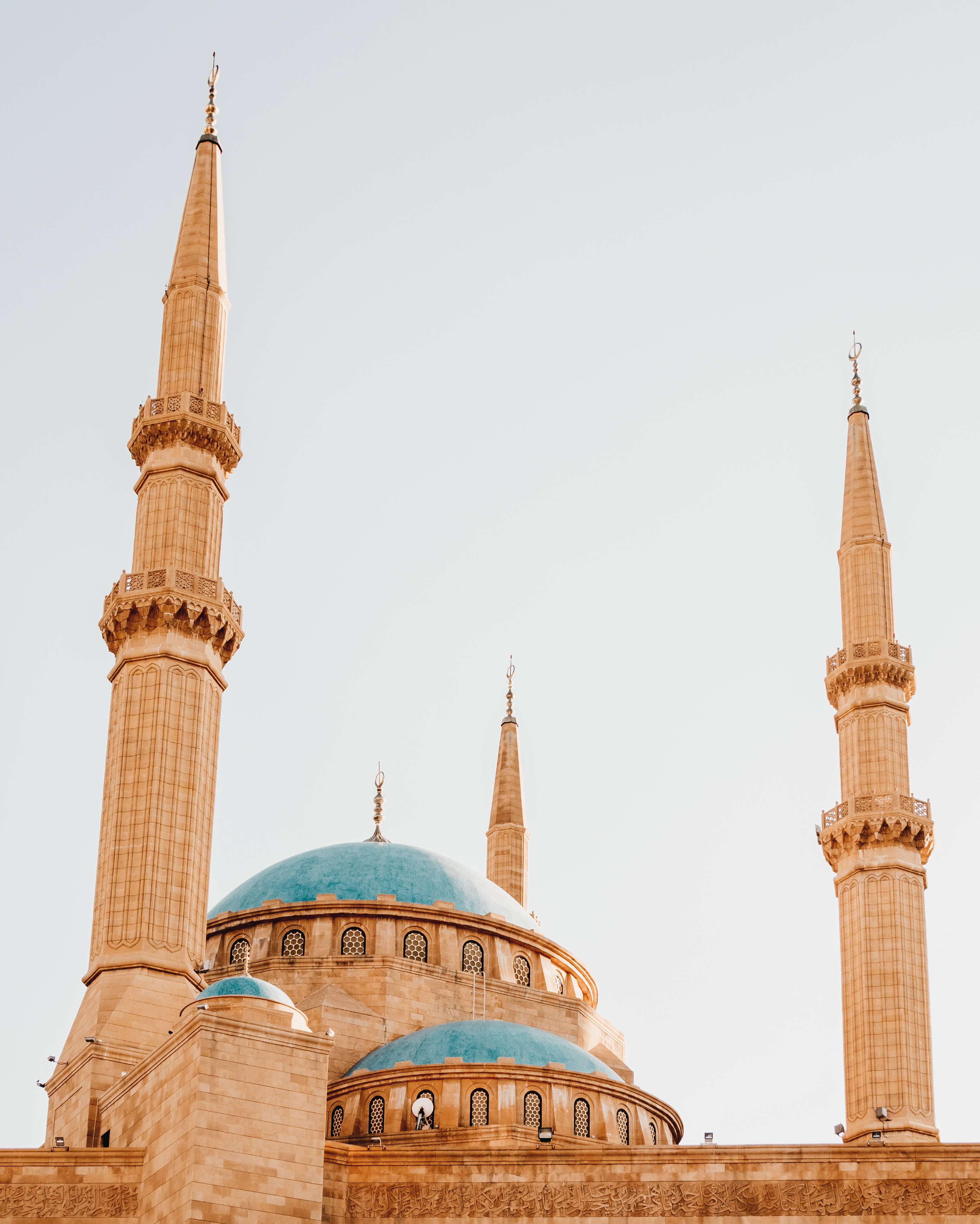 Lebanon 桌布 壁紙 — 宏偉的清真寺，擁有藍綠色圓頂和高聳的宣禮塔，在蒼白的天空下沐浴在溫暖的金色光芒中。