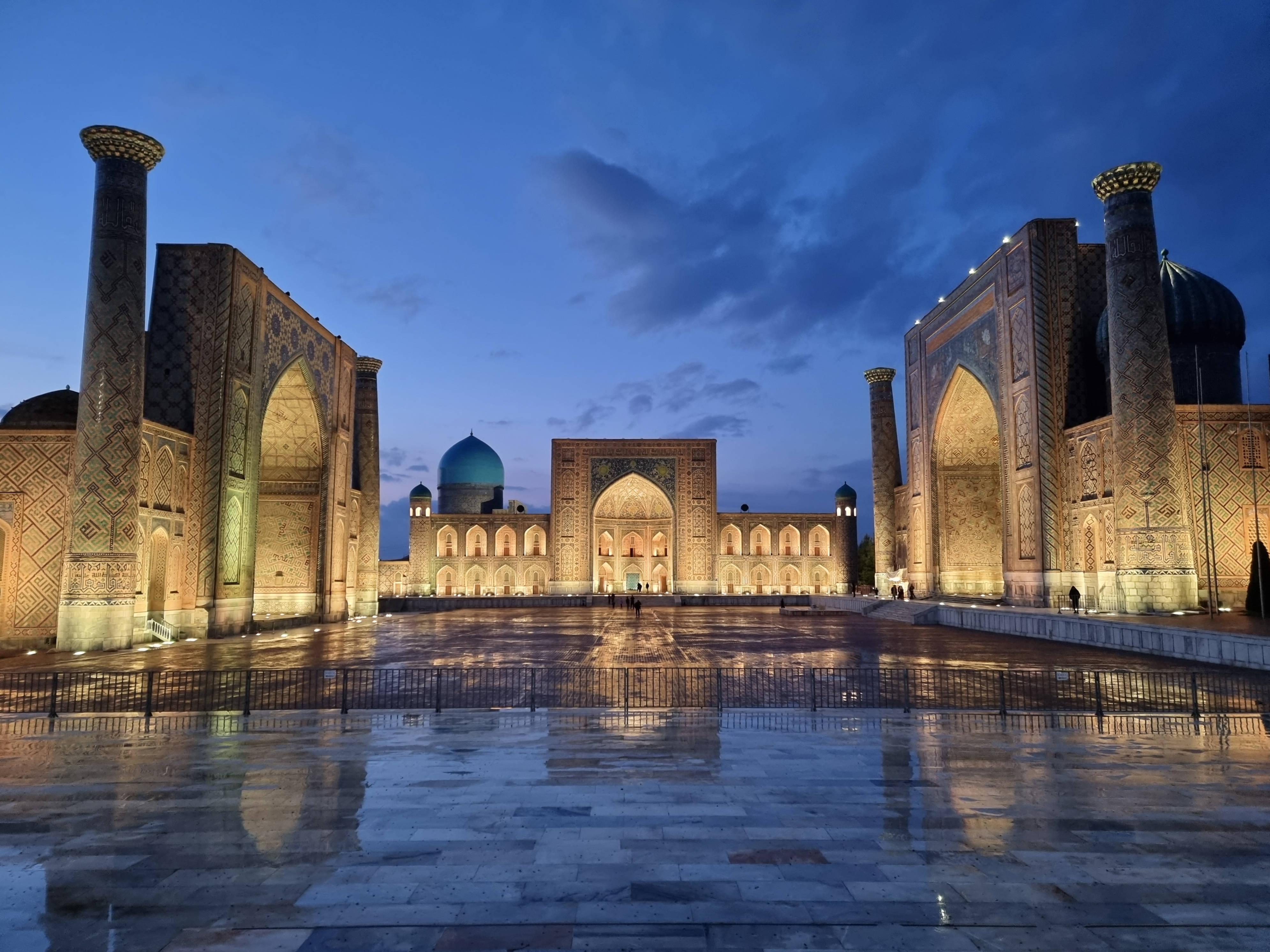 Uzbekistan 桌布 壁紙 — 宏偉的燈光伊斯蘭建築在暮色天空下倒映在濕漉漉的石頭廣場上。