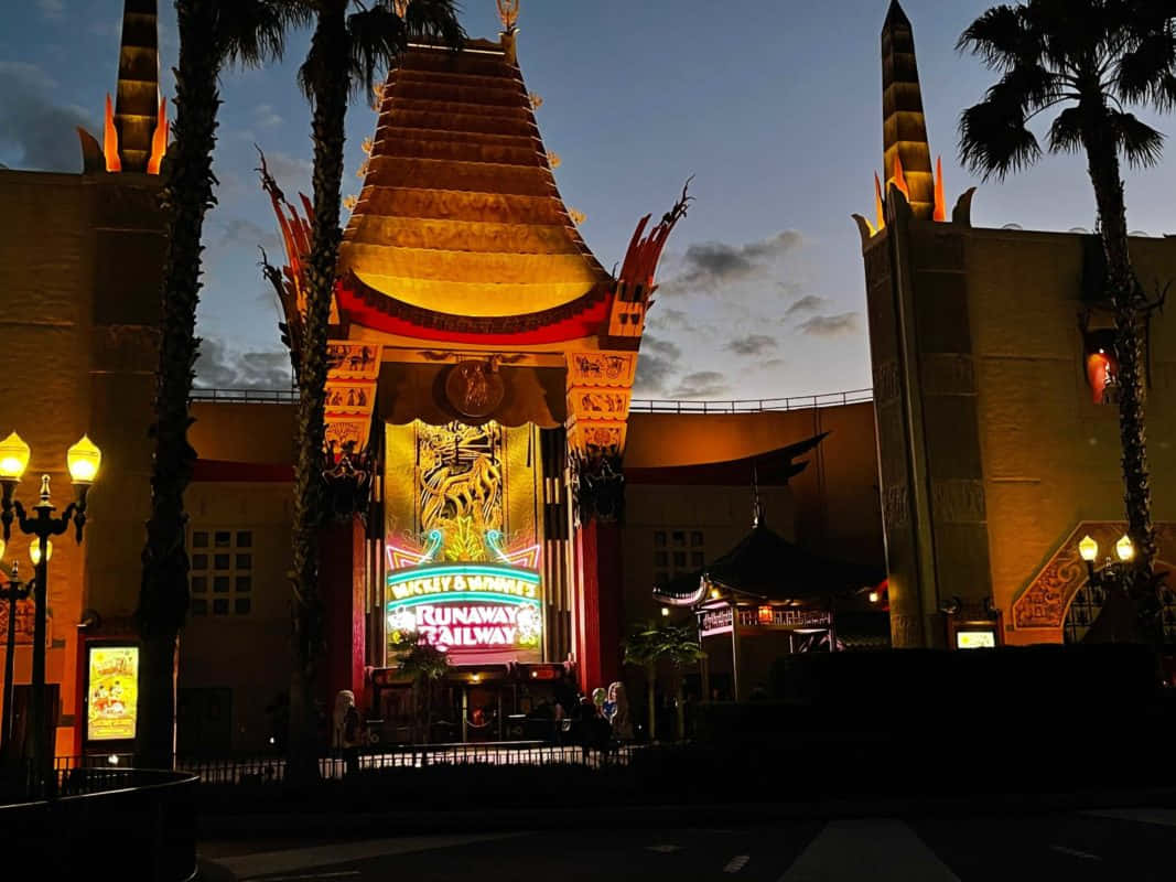 hollywood street 桌布 壁紙 — 宏偉的燈光劇院外牆在黃昏時分溫暖地發光，周圍環繞著棕櫚樹和街燈。