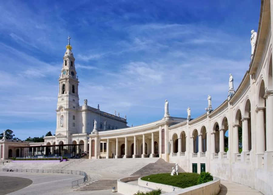 Portugal 桌布 壁紙 — 宏偉的白色大教堂，擁有高聳的鐘樓和拱形柱廊，在明亮的藍天下飄著縷縷白雲。