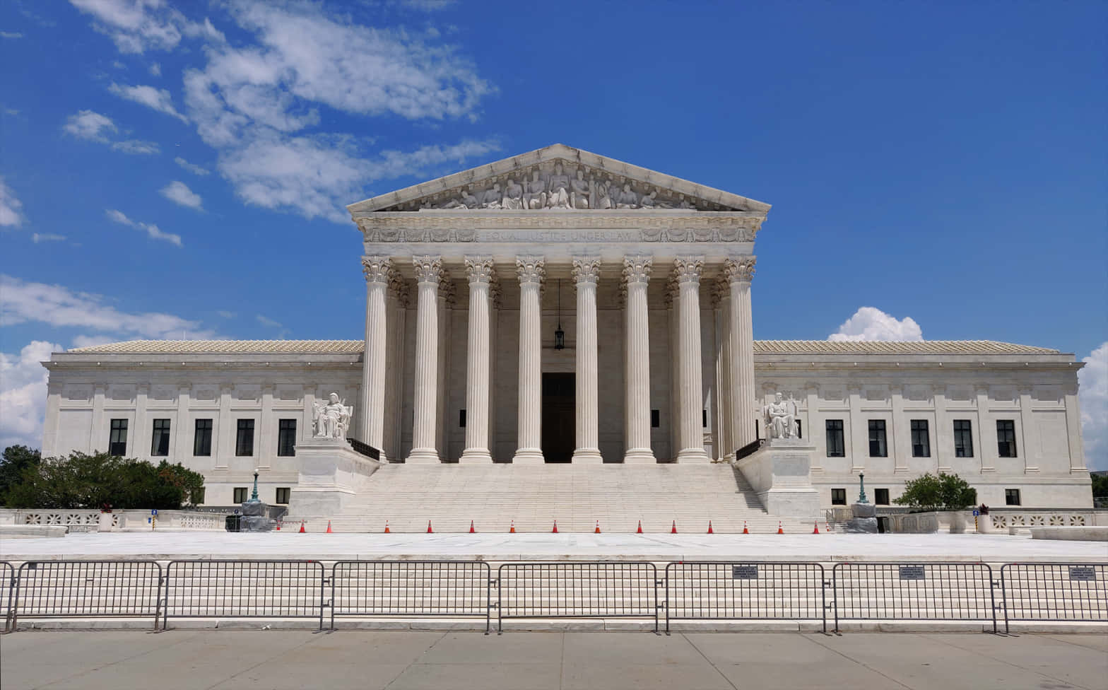 Law 桌布 壁紙 — 宏偉的白色新古典主義最高法院建築，在明亮的藍天下，有零星雲朵和前景的金屬路障。