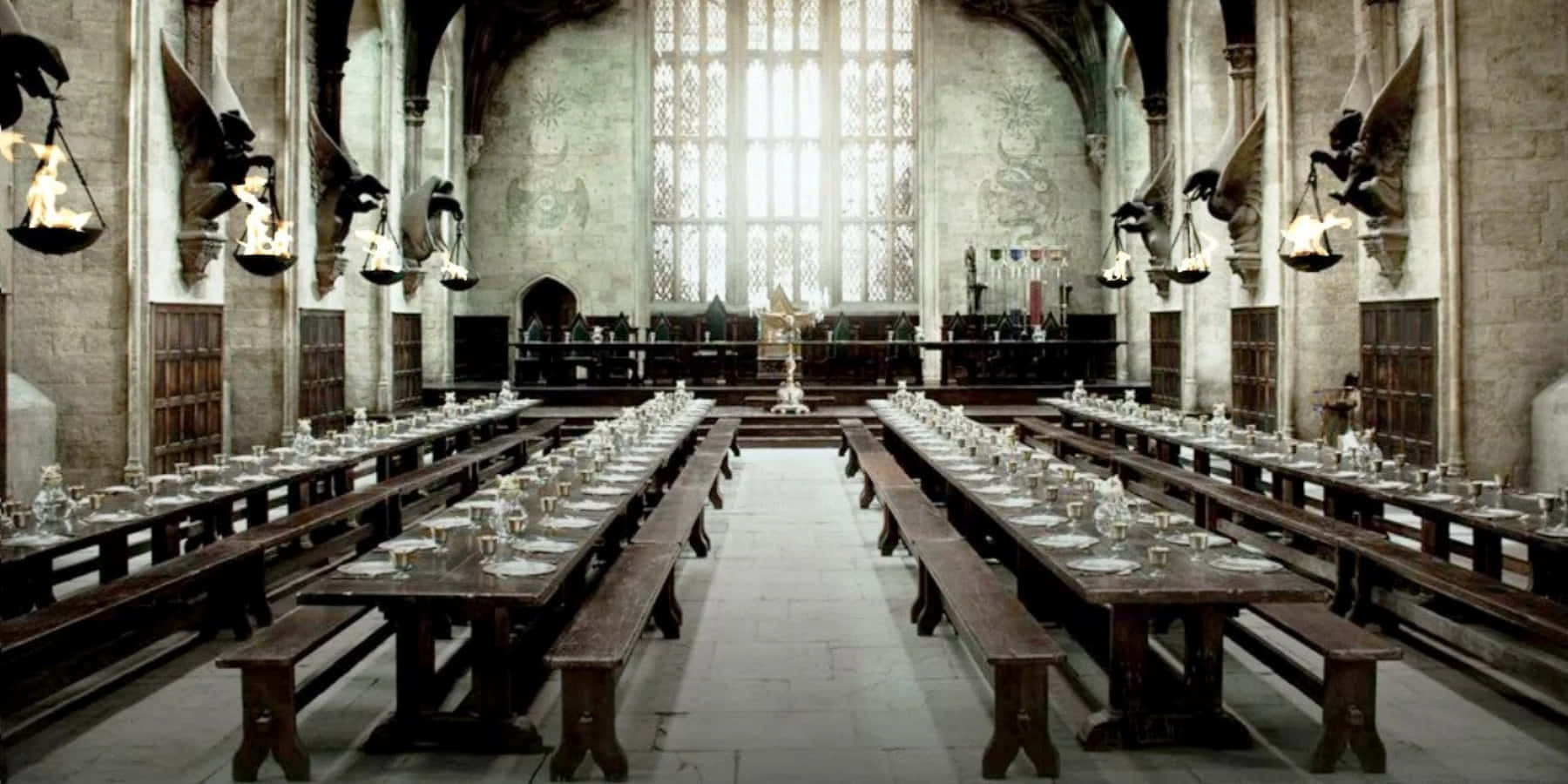 The Hogwarts Great Hall 桌布 壁紙 — 宏偉的石廳，長木桌擺設好供用餐，上方有彩繪玻璃窗和漂浮蠟燭。