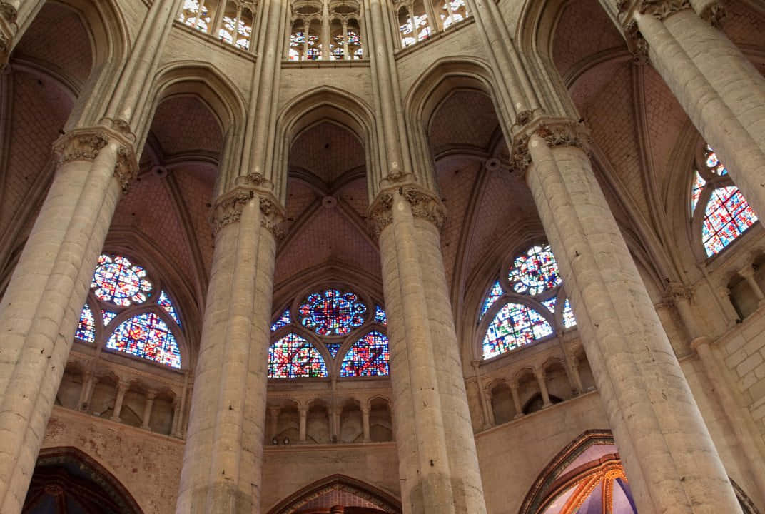 Gothic Architecture 桌布 壁紙 — 宏偉的石柱聳立向拱形天花板，被哥德式大教堂中鮮豔的彩繪玻璃窗穿透。