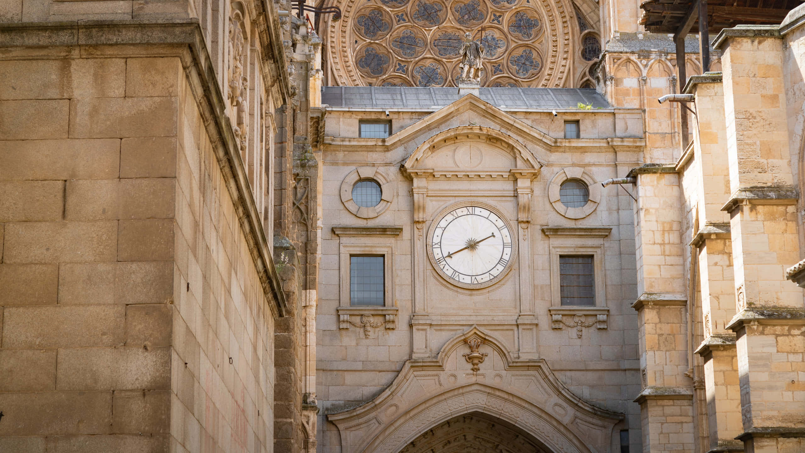Clock 桌布 壁紙 — 宏偉的石造大教堂正面，在華麗的玫瑰窗和拱形入口下方有一個大時鐘。