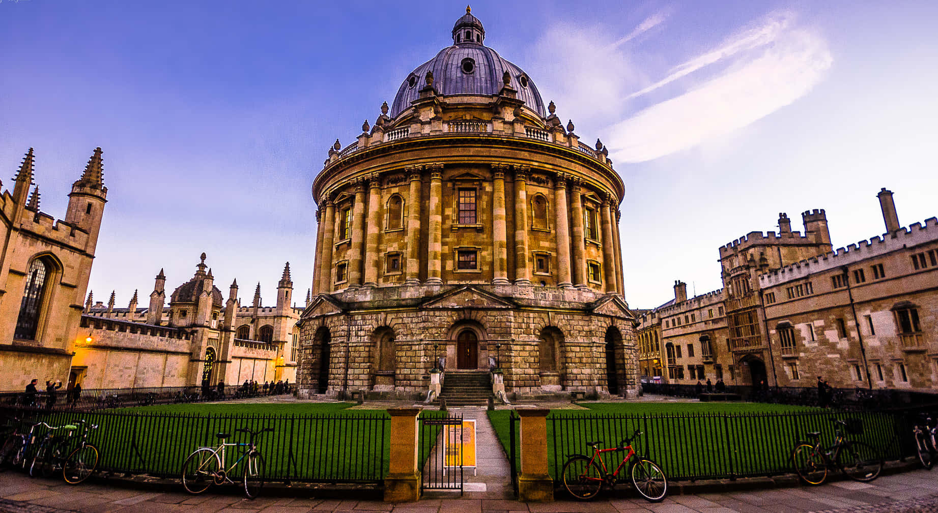 England 桌布 壁紙 — 宏偉的石造拉德克利夫相機大樓，圓頂屋頂在黃昏時雄偉矗立，周圍是歷史建築和停放的自行車。