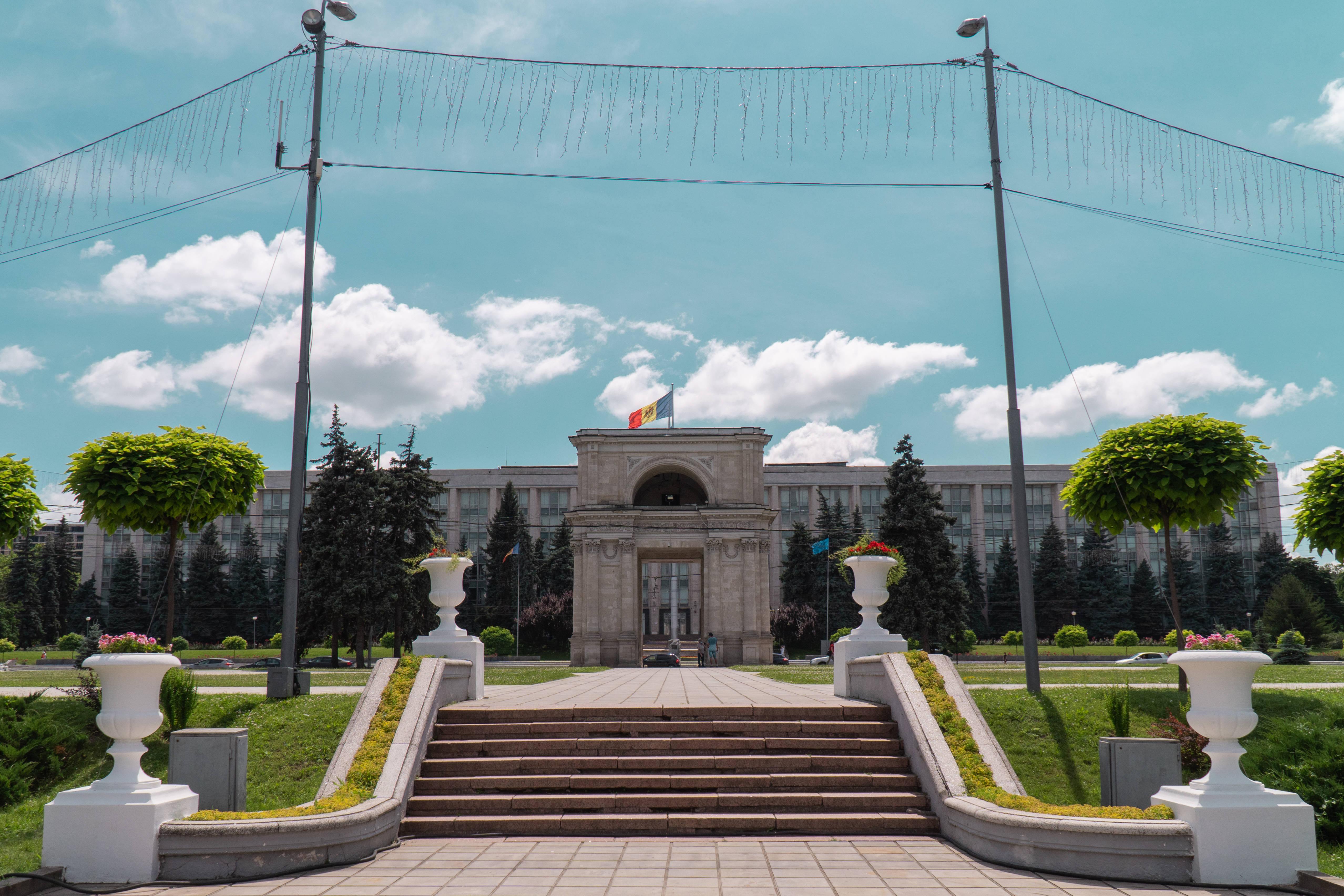 Moldova 桌布 壁紙 — 宏偉的石階通往一座新古典主義建築，上方是晴朗的藍天和蓬鬆的白雲。