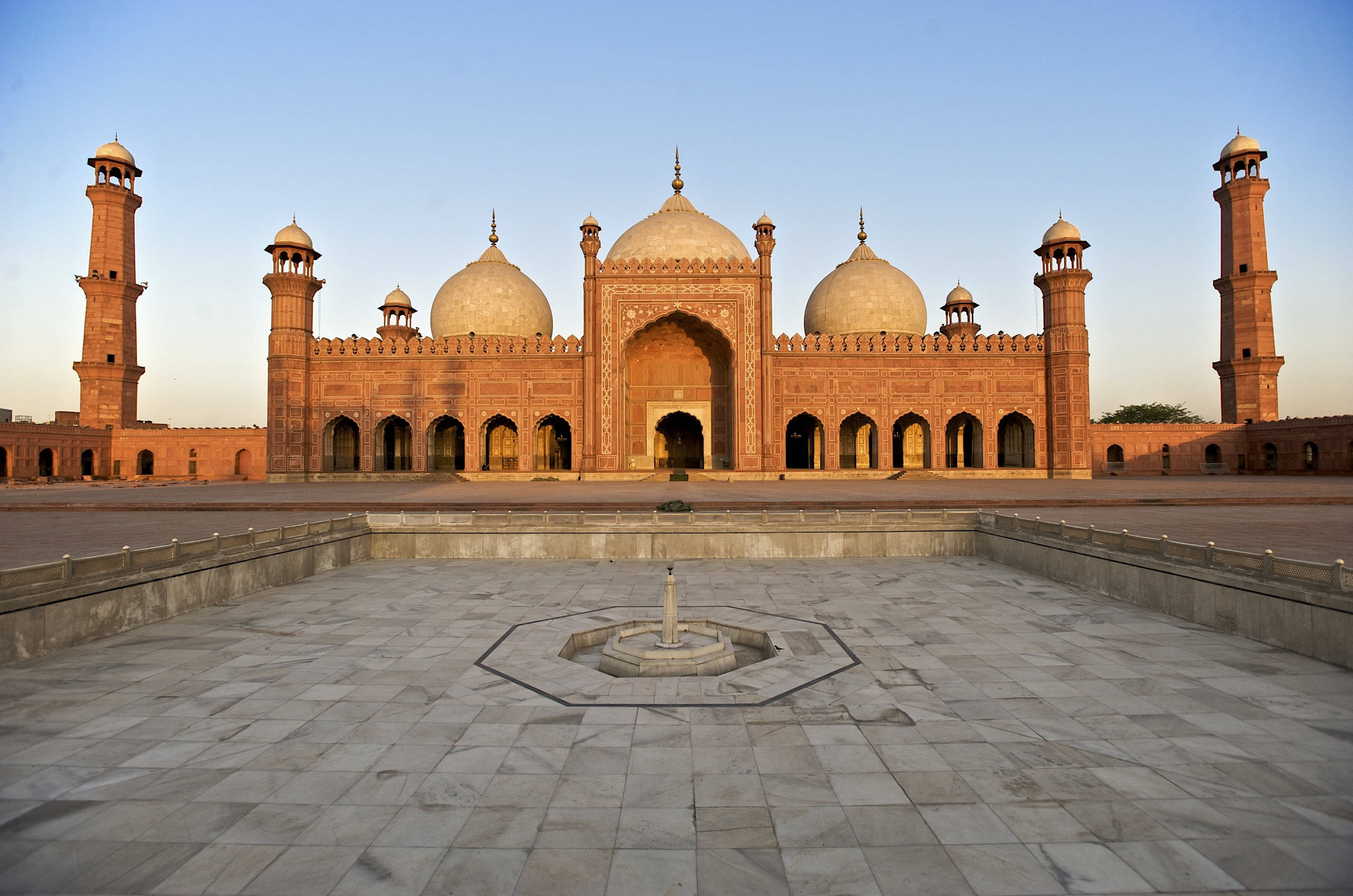 Pakistan 桌布 壁紙 — 宏偉的紅色砂岩清真寺，圓頂和宣禮塔沐浴在金色的日落光芒中。