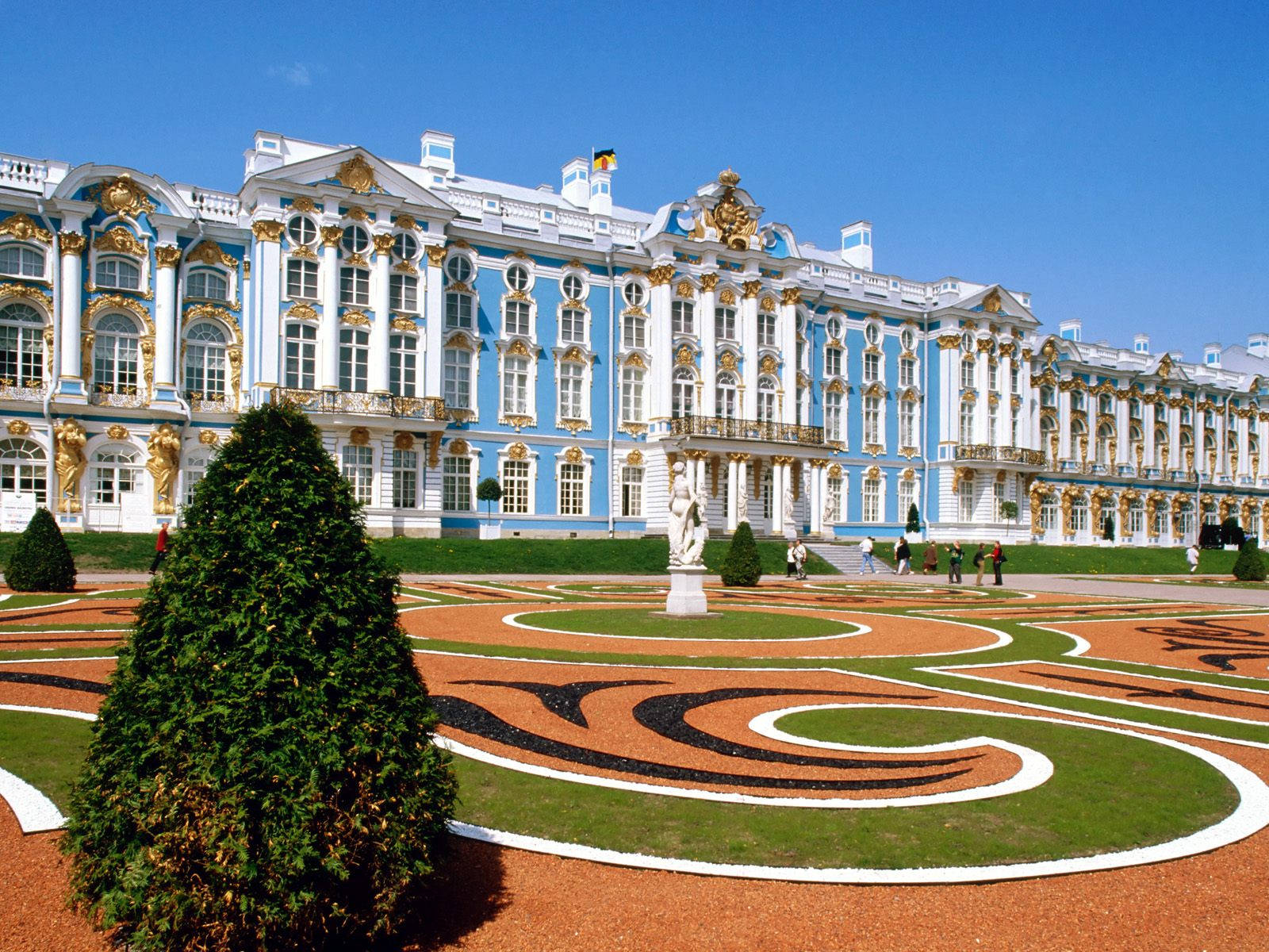 Russia 桌布 壁紙 — 宏偉的藍金色宮殿，裝飾華麗的建築俯瞰著精心修剪的花園，蜿蜒的碎石小徑和修剪整齊的樹籬在清澈的藍天下。