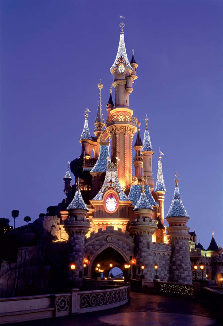 Disneyland Castle 桌布 壁紙 — 宏偉的迪士尼城堡在深暮色天空下被溫暖燈光照亮。