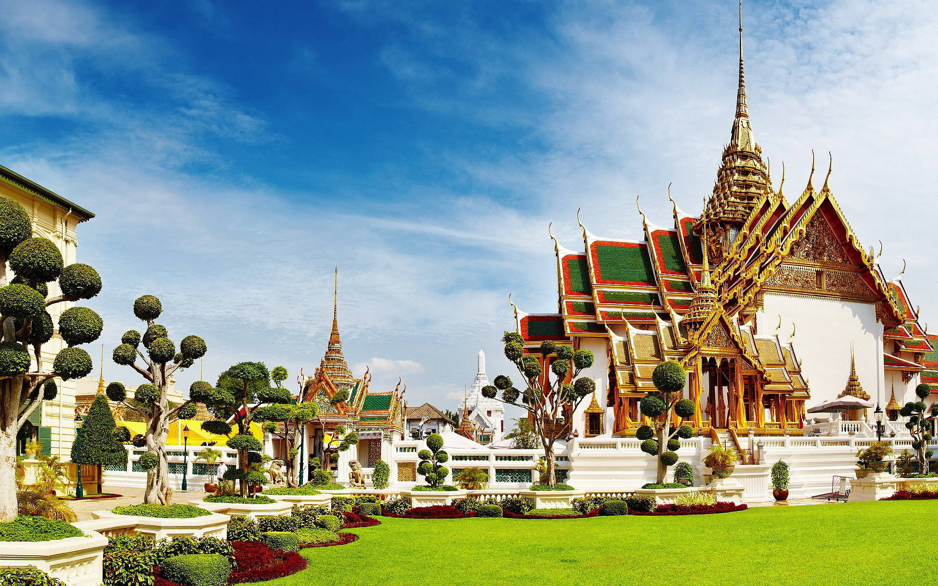 Bangkok 桌布 壁紙 — 宏偉的金色寺廟，擁有精緻的尖頂和充滿活力的綠色屋頂，在藍天白雲下雄偉地矗立。