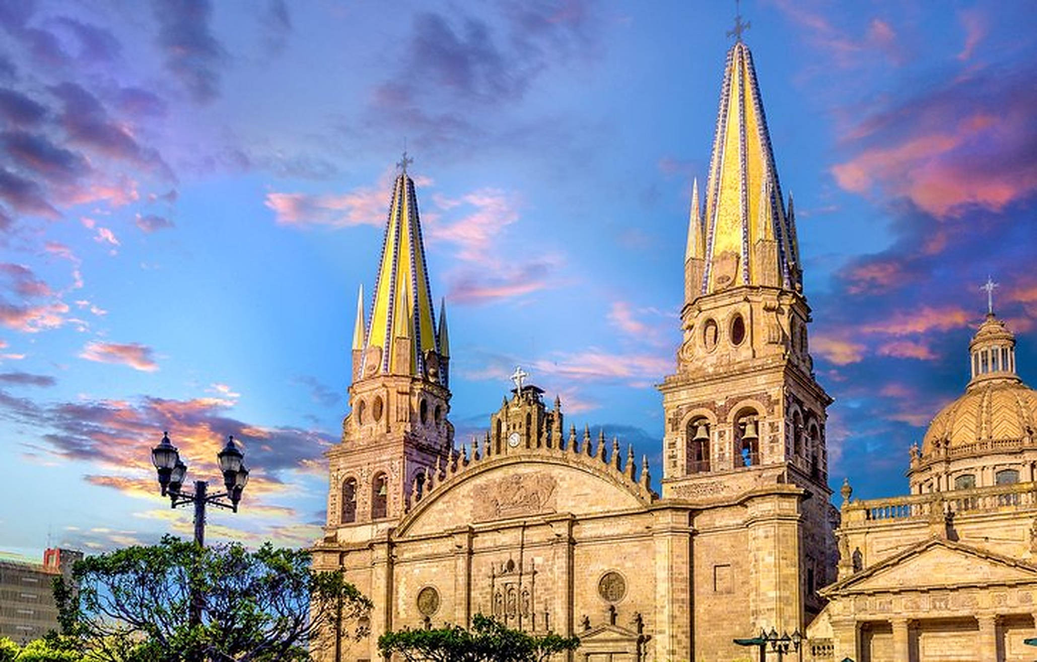 Guadalajara 桌布 壁紙 — 宏偉的雙塔大教堂沐浴在金色夕陽的光芒中，映襯著充滿活力的紫色和粉紅色天空。