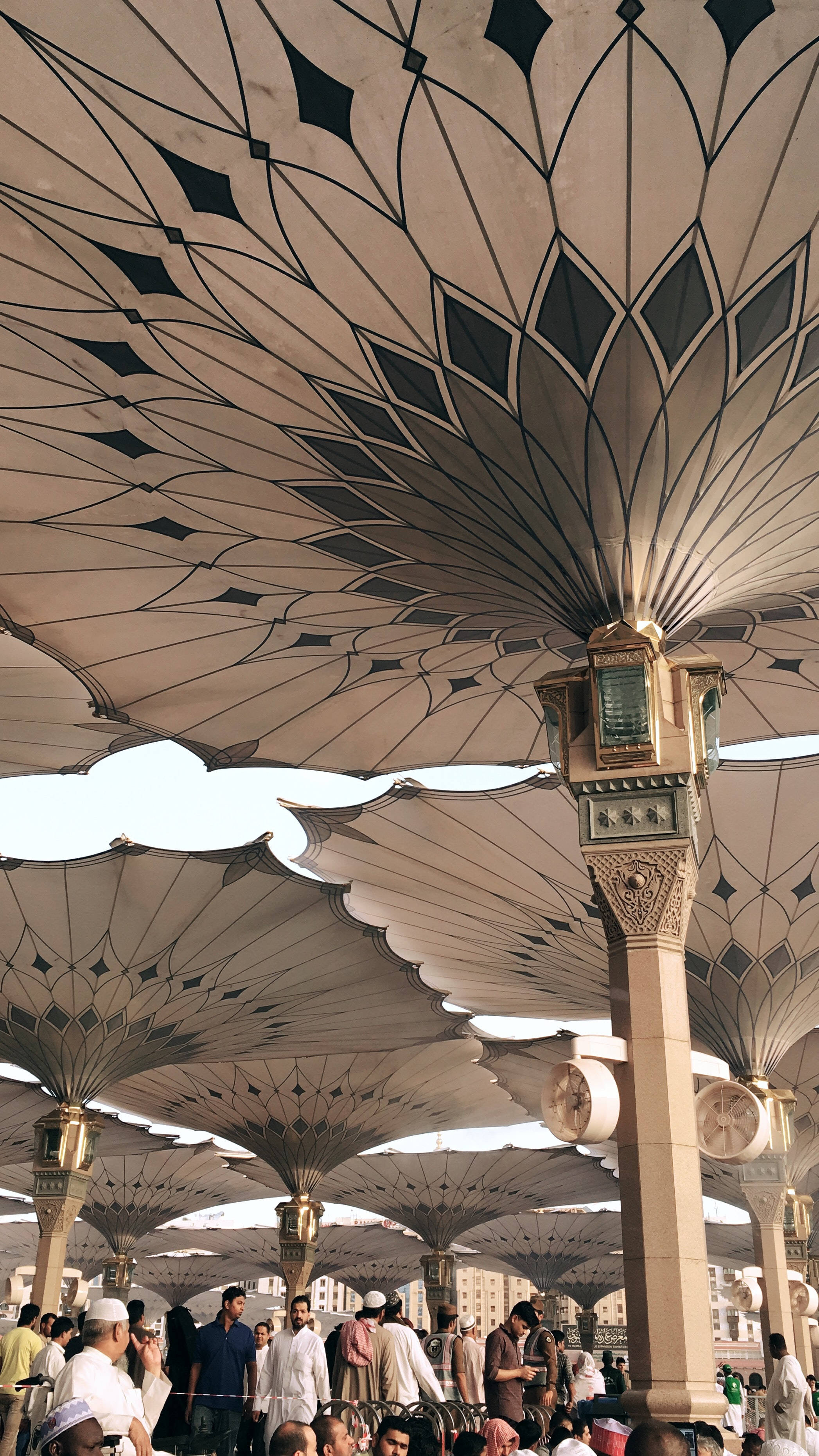 Madina 桌布 壁紙 — 宏偉華麗的幾何圖案天篷結構，在陽光普照的城市廣場上為熙攘的人群遮蔭。