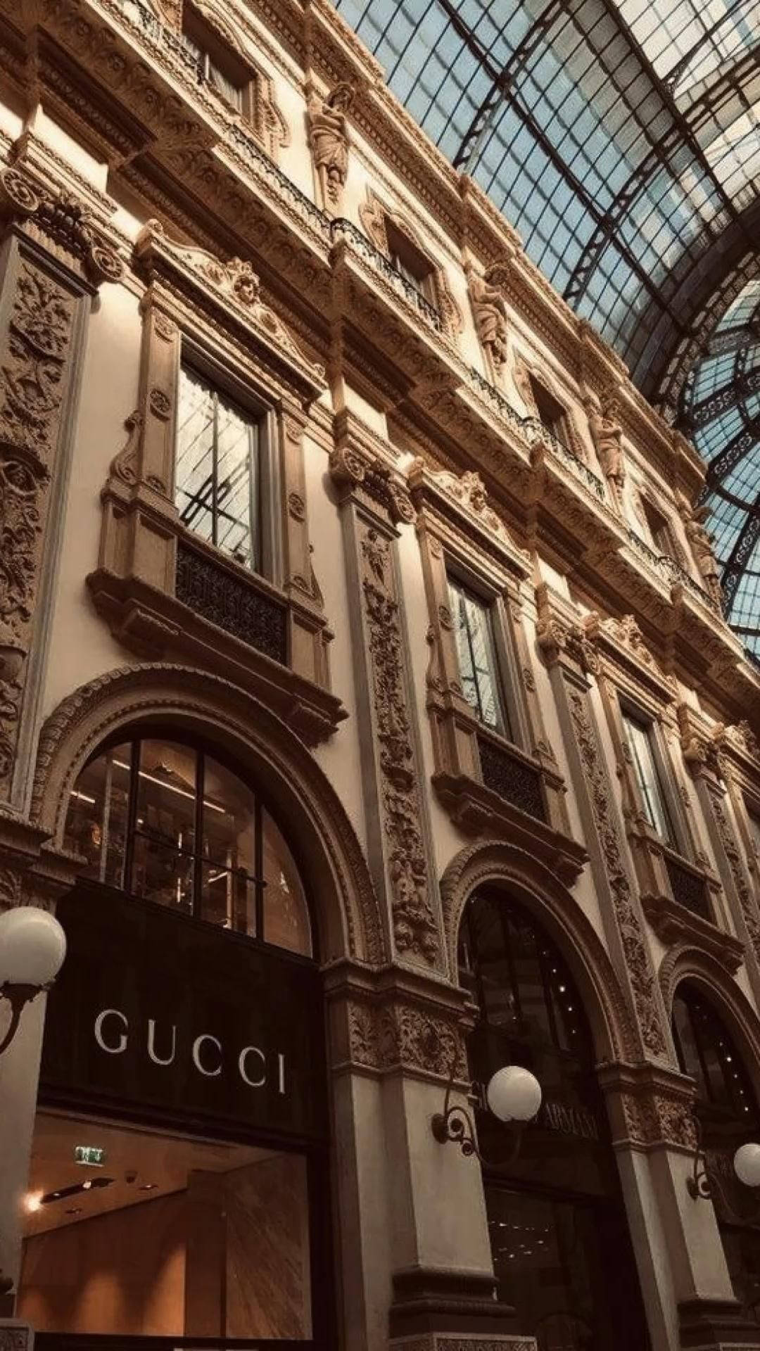 淺棕色美學動圖 桌布 壁紙 — 宏偉華麗的拱廊，Gucci 商店位於玻璃穹頂下，沐浴在溫暖的金色光芒中。