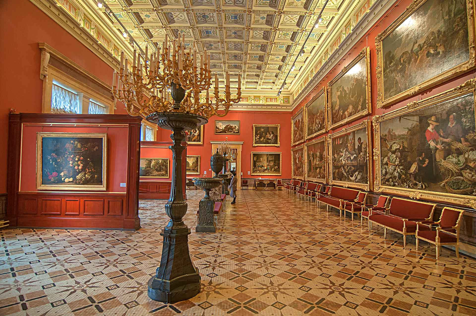 Museum 桌布 壁紙 — 宏偉華麗的畫廊，紅色牆壁，金色框架畫作，以及照亮圖案瓷磚地板的 towering 吊燈。