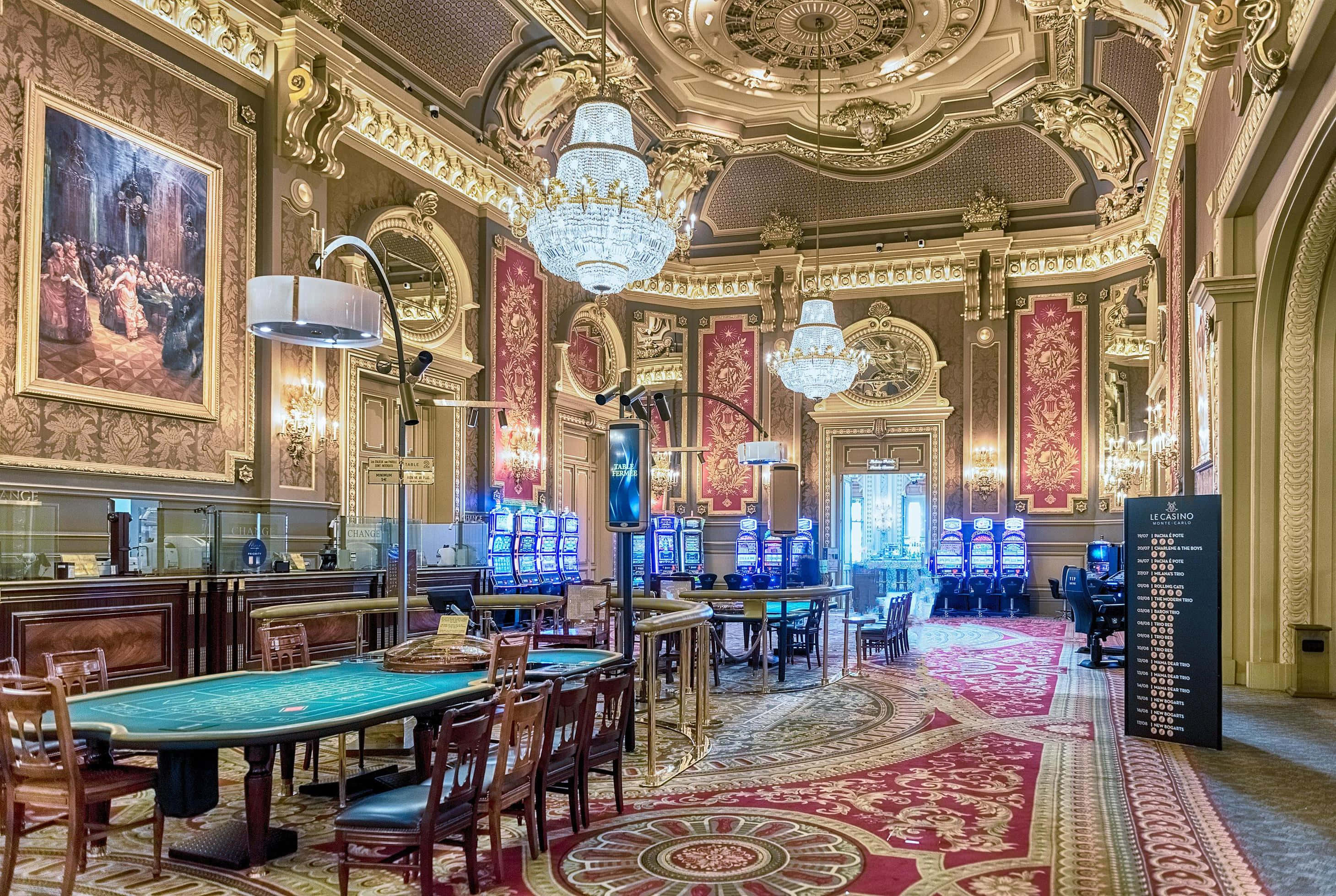 Monaco 桌布 壁紙 — 宏偉華麗的賭場大廳，飾有金色天花板、吊燈、紅色地毯地板和賭桌，在溫暖的環境燈光下。