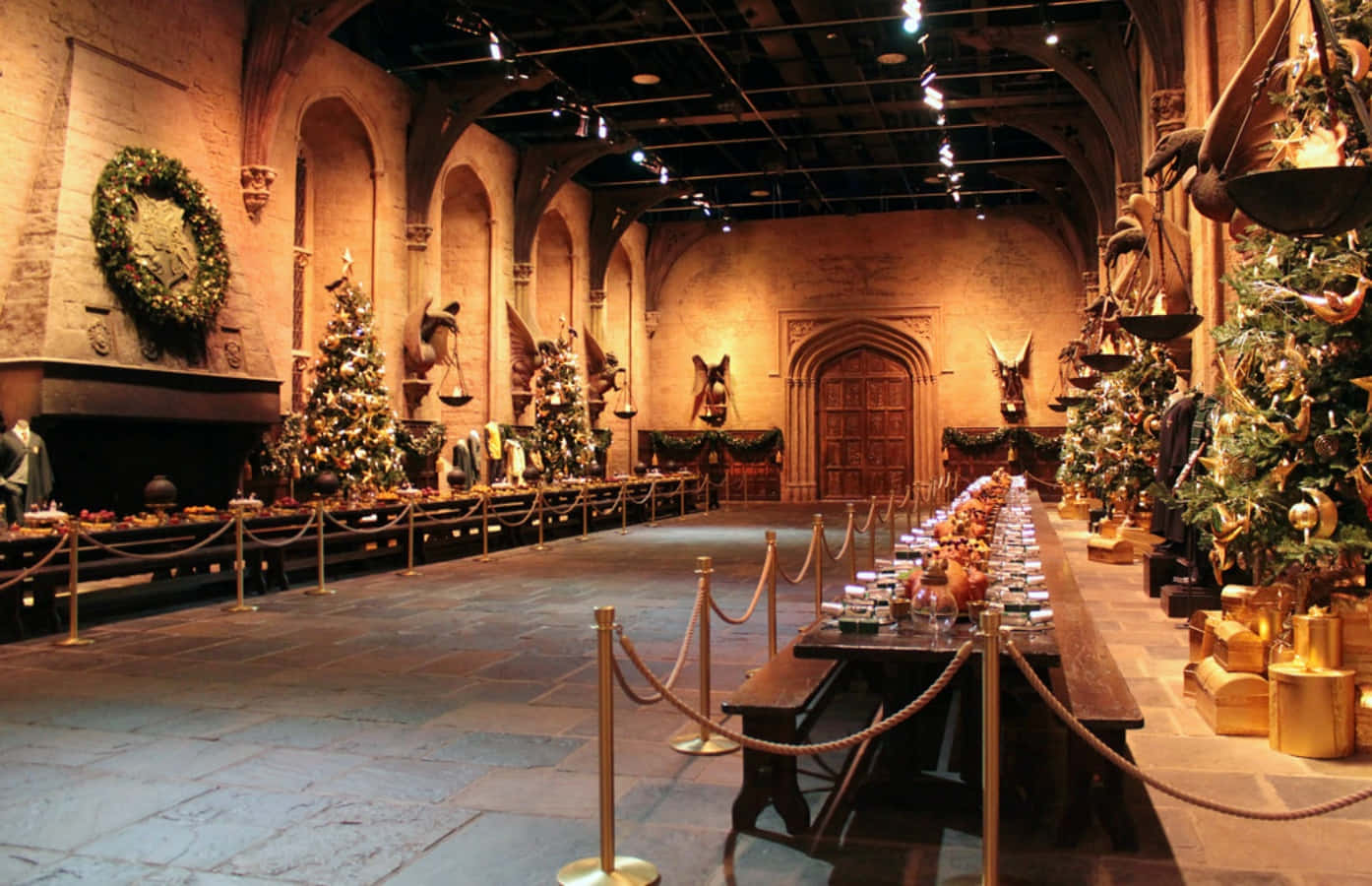 The Hogwarts Great Hall 桌布 壁紙 — 宏大的霍格華茲大禮堂裝飾成聖誕節，有高聳的樹木、金色裝飾和節日餐桌，在溫暖閃爍的燈光下。