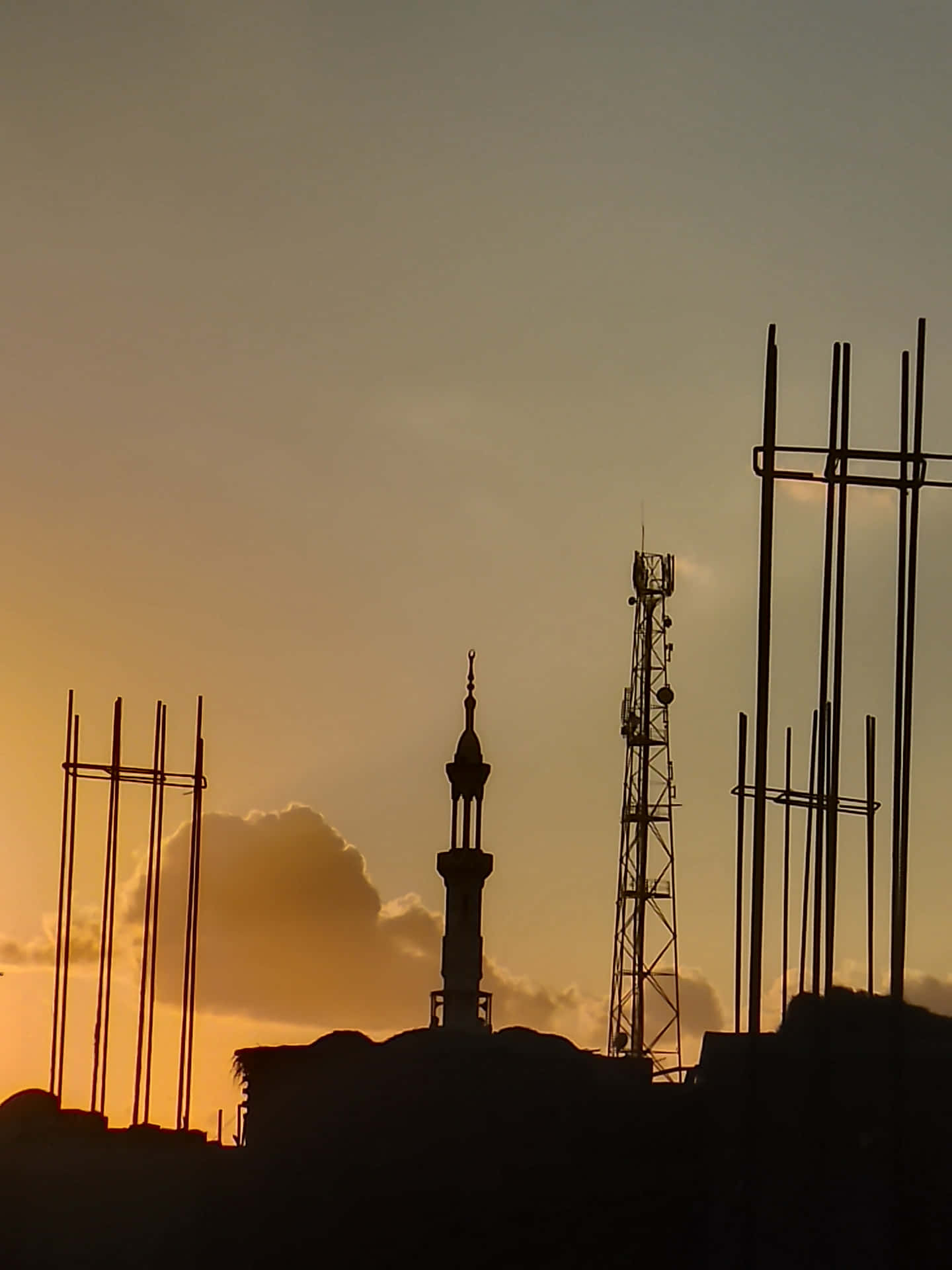 wallpaper 壁紙 — 宣禮塔和通訊塔的剪影在金色夕陽天空下升起，周圍是建築鋼筋。