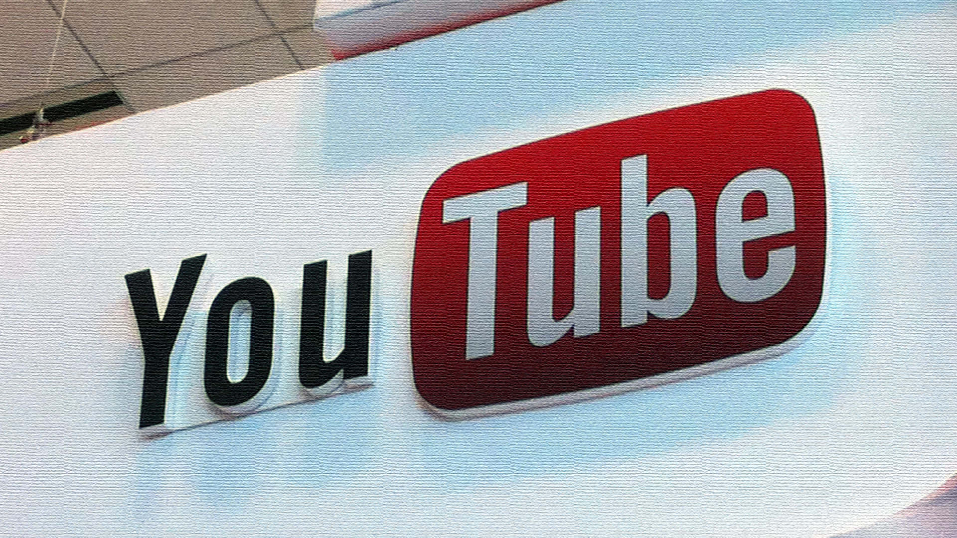 YouTube Logo 桌布 壁紙 — 室內燈光下，白色牆上安裝的紅白三維YouTube標誌特寫。