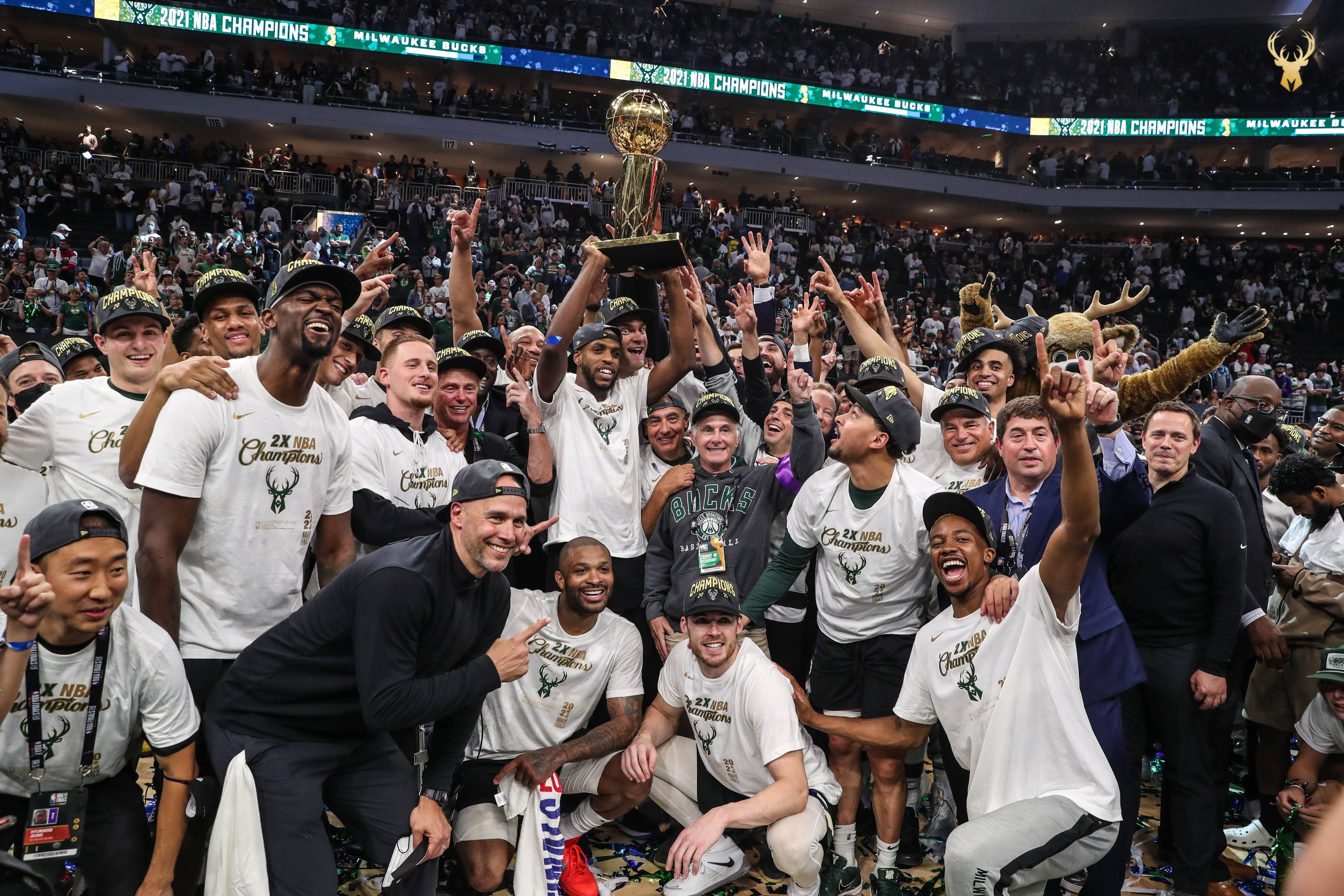 Bucks 桌布 壁紙 — 密爾瓦基公鹿籃球隊慶祝贏得2021年NBA總冠軍，在場館內高舉獎盃，周圍有五彩紙屑和歡呼的球迷。