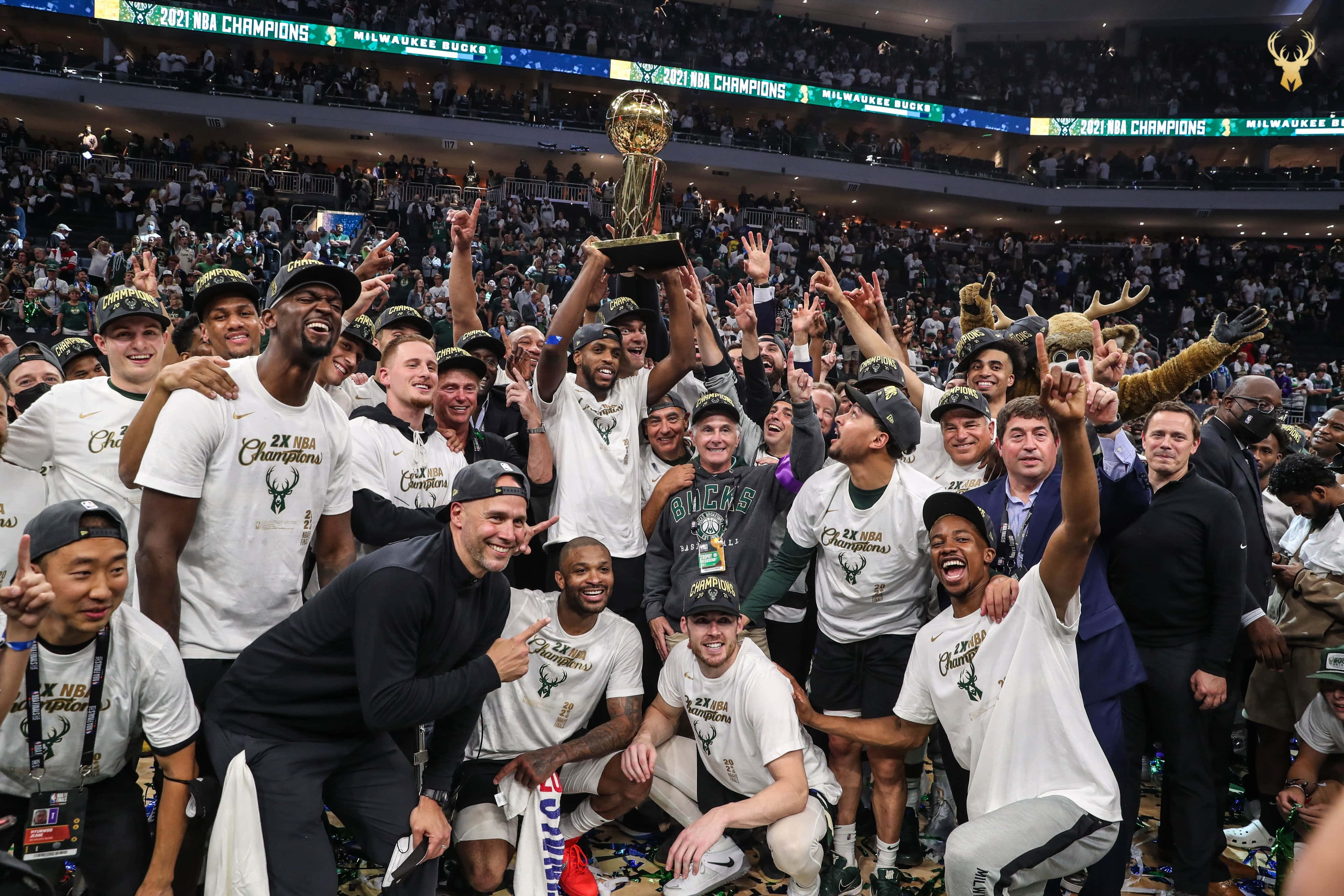Milwaukee Bucks Logo 桌布 壁紙 — 密爾瓦基公鹿籃球隊慶祝贏得2021年NBA總冠軍，在場館內舉起獎盃，周圍有五彩紙屑和歡呼的球迷。