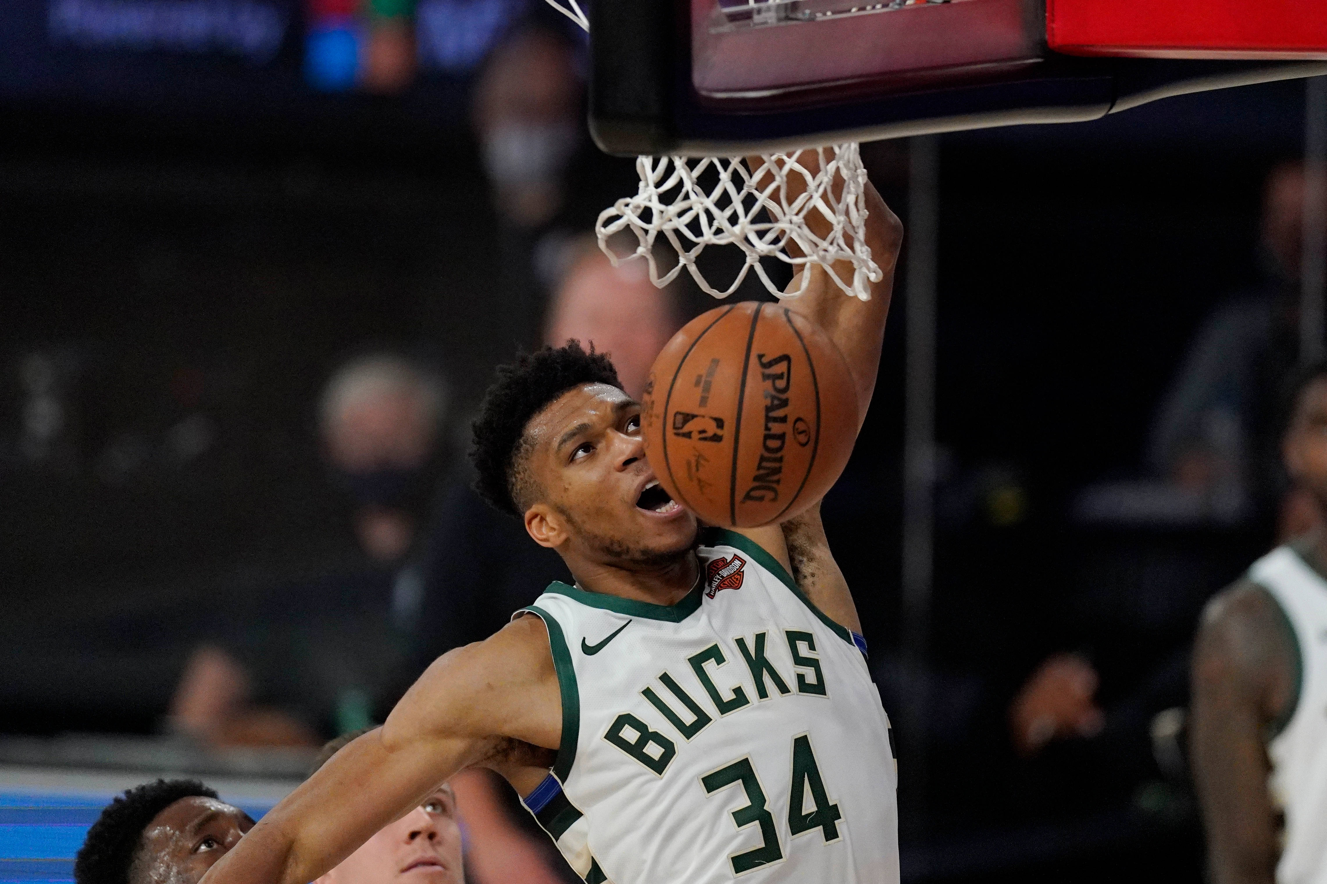 Giannis 桌布 壁紙 — 密爾瓦基公鹿隊34號球員在夜間比賽中專注地灌籃Spalding籃球。
