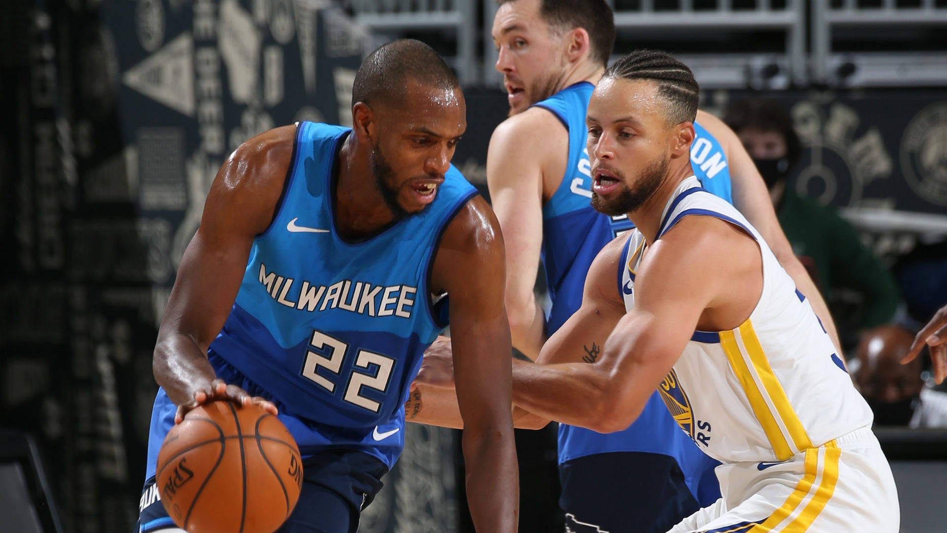 Khris Middleton 桌布 壁紙 — 密爾瓦基公鹿隊球員在激烈的籃球比賽中運球，同時被金州勇士隊球員緊密防守。