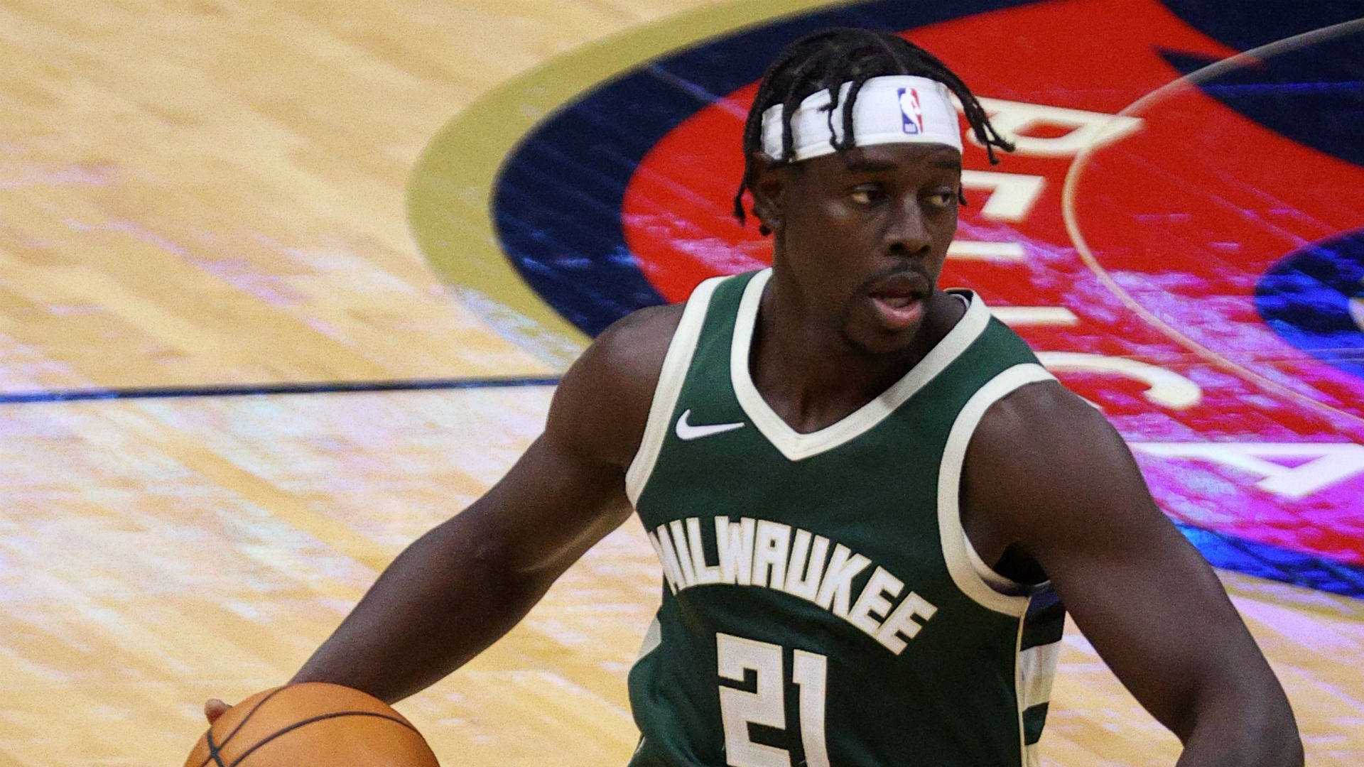 Jrue Holiday 桌布 壁紙 — 密爾瓦基公鹿隊籃球球員身穿綠色球衣，在硬木球場上激烈運球。