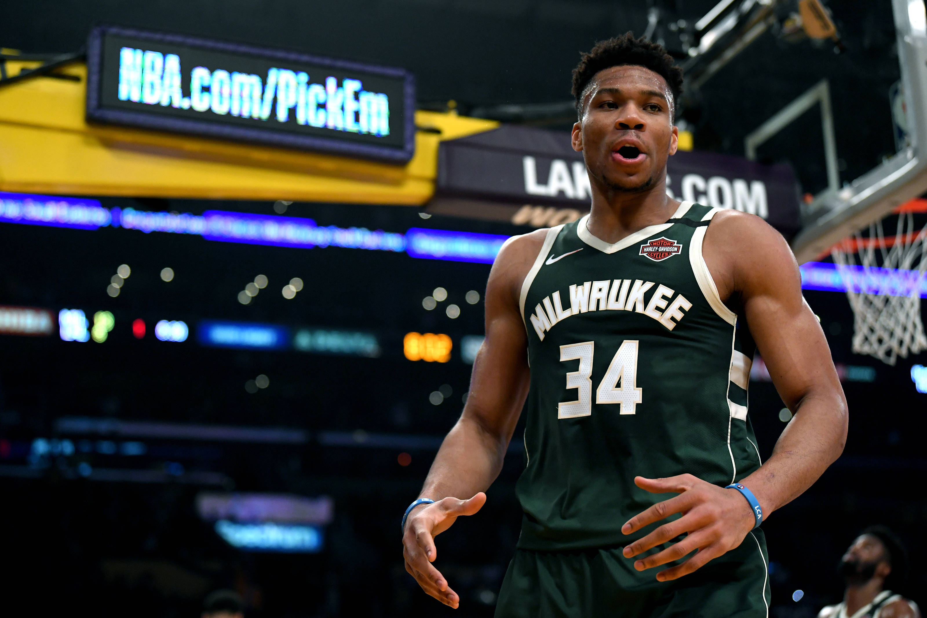 Giannis 桌布 壁紙 — 密爾瓦基公鹿隊籃球運動員身穿綠色34號球衣，在場館燈光下比賽中激烈反應。